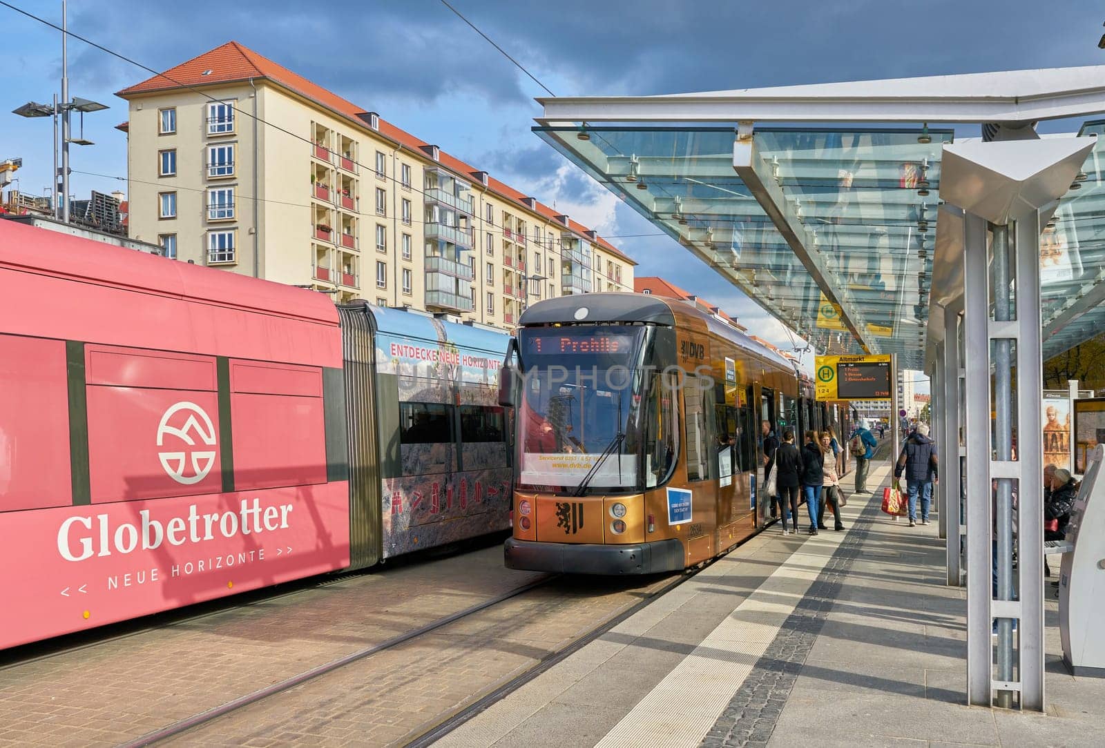 People at a tram stop in the busy city center of Dresden