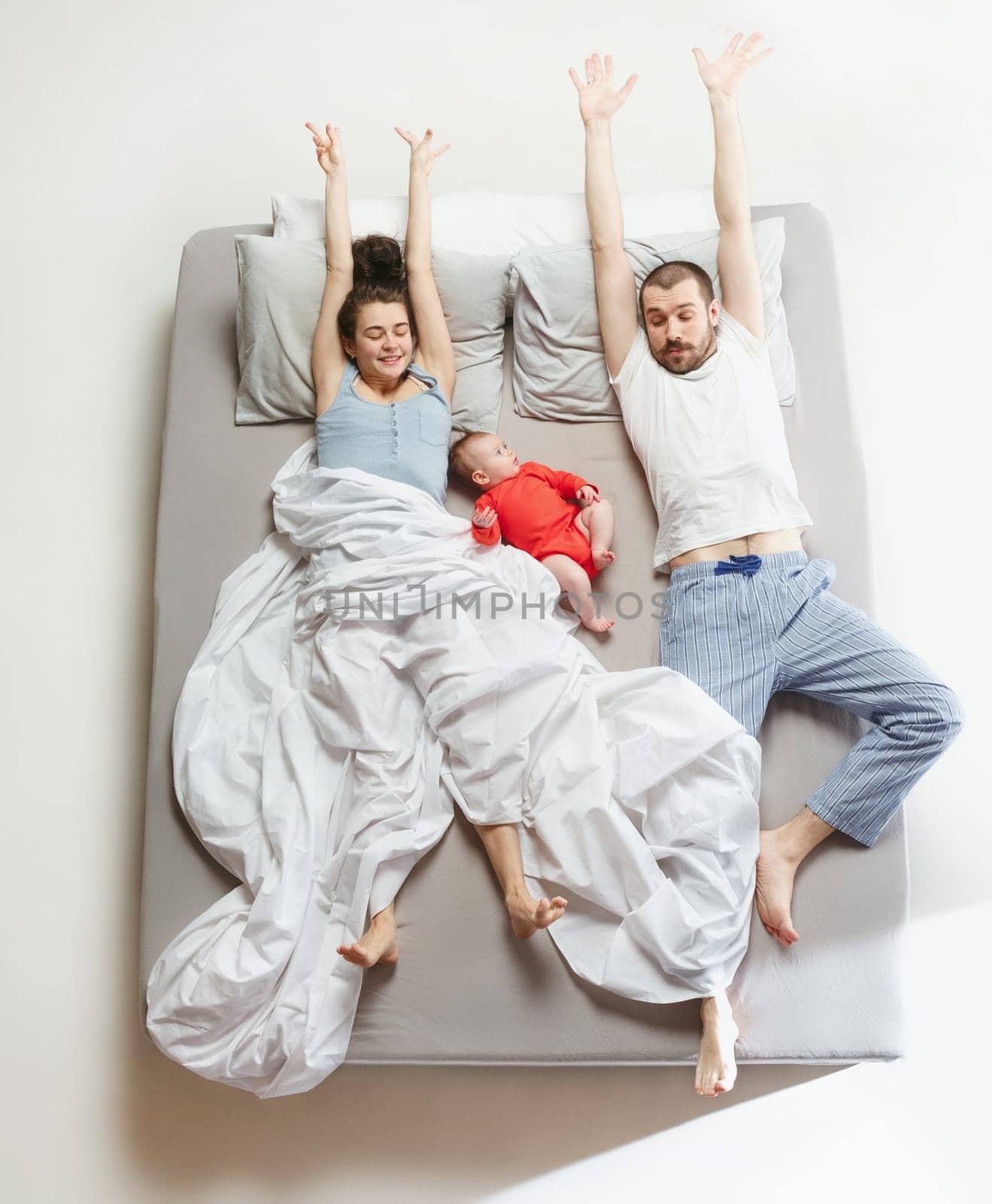 Top view of happy funny family with one newborn child in bedroom. Enjoying being together. Happy family in bed. Top view. Emotions concept. Morning after sleep. Family lifestyle. happy parents concept