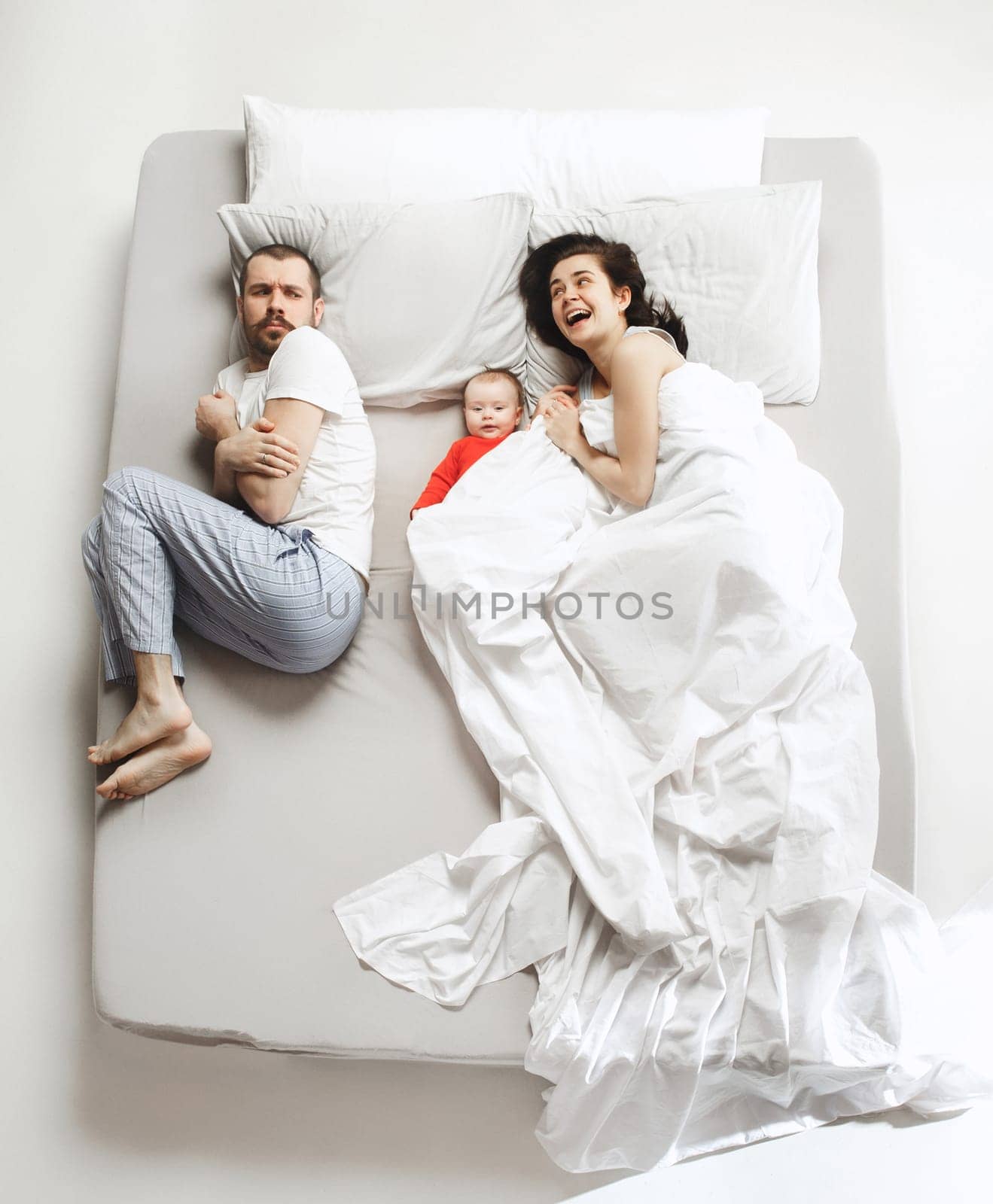 Top view of happy funny family with one newborn child in bedroom. Enjoying being together. Happy family in bed. Top view. Emotions concept. Morning after sleep. Family lifestyle. happy parents concept