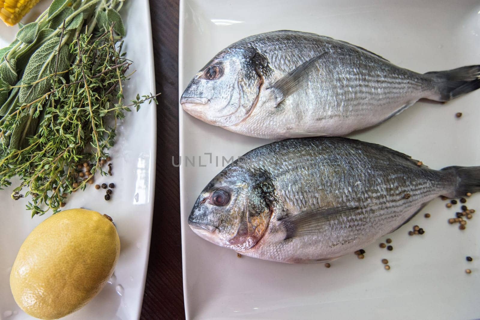 Fresh uncooked dorado with lemon, herbs, oil and spices ready for preparing