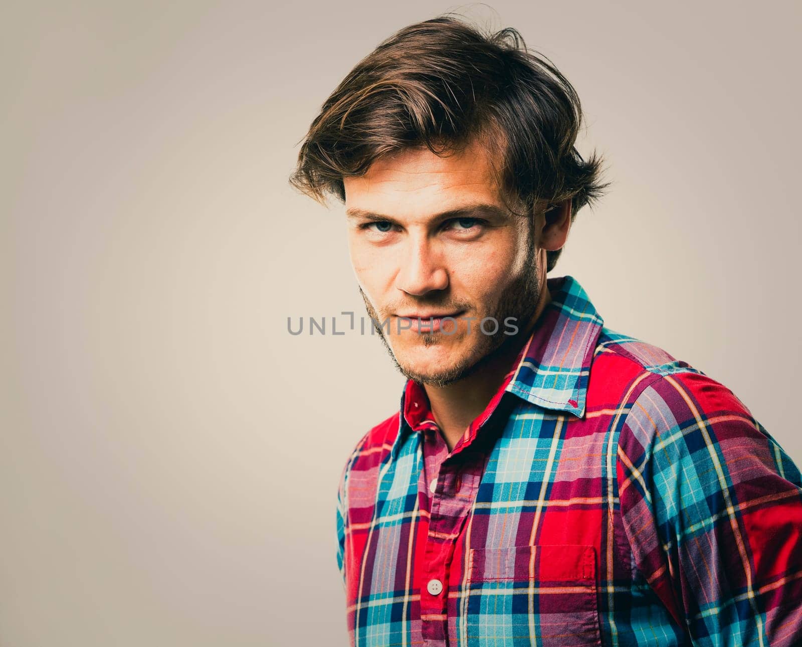 Fashion portrait of a handsome man with trendy hairstyle in a stylish shirt on light green background