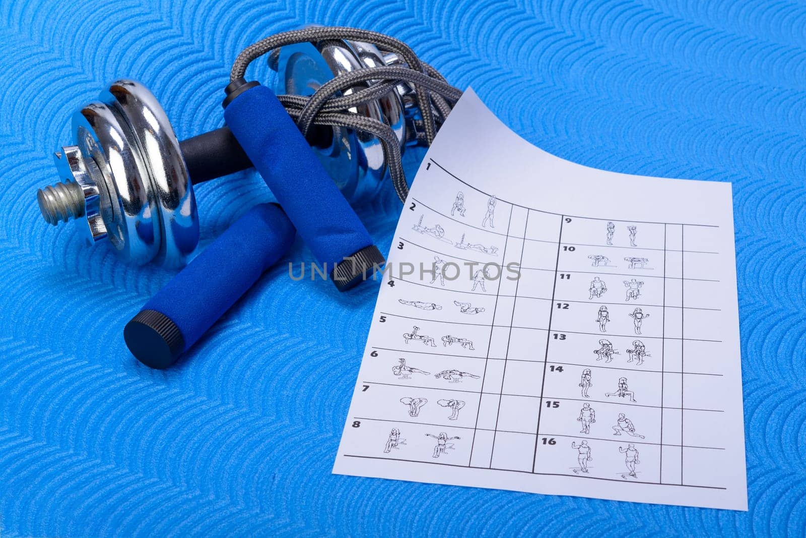 Sports fitness accessories on blue training mat. Table of gymnastic exercises with white space.