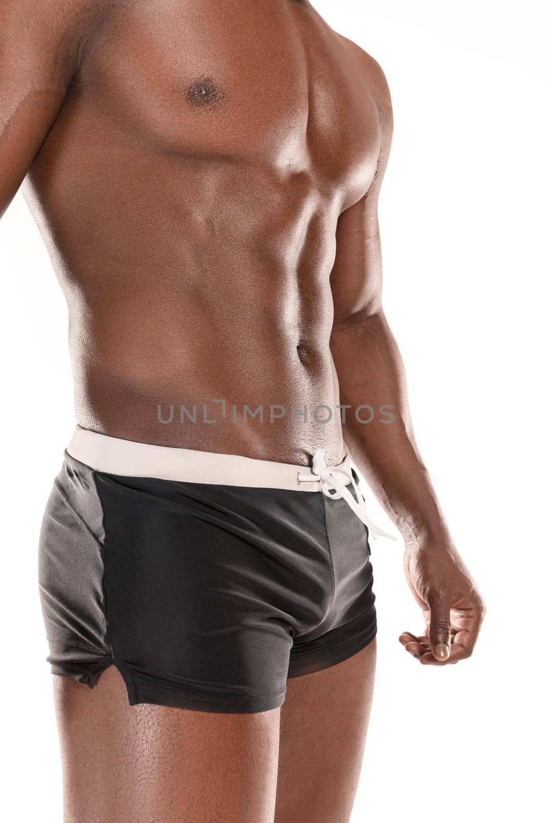 Fit young man with beautiful torso, isolated on white background. The naked torso of African American man posing at studio. The muscular body, fitness, sports, healthy lifestyle and bodybuilder concept.