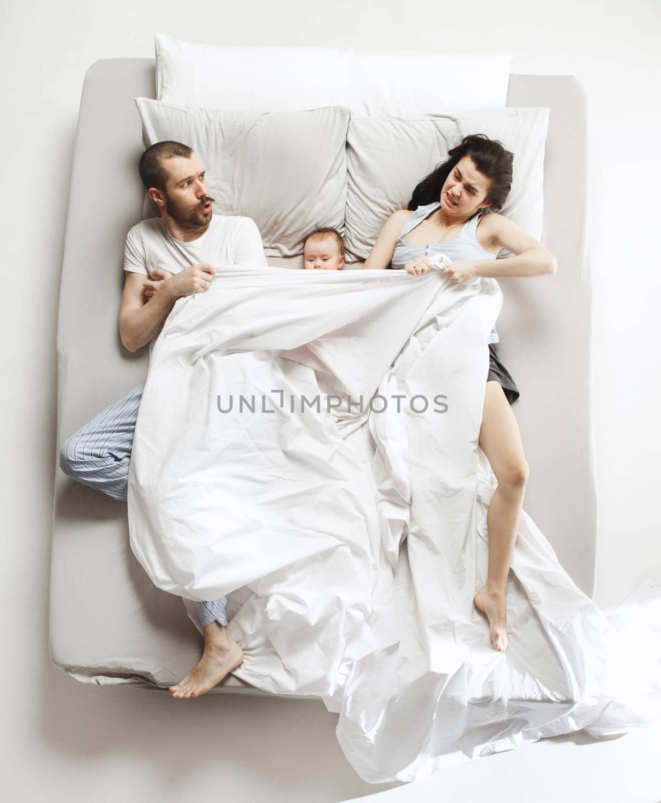 Top view of happy funny family with one newborn child in bedroom. Enjoying being together. Happy family in bed. Top view. Emotions concept. Morning after sleep. Family lifestyle. happy parents concept