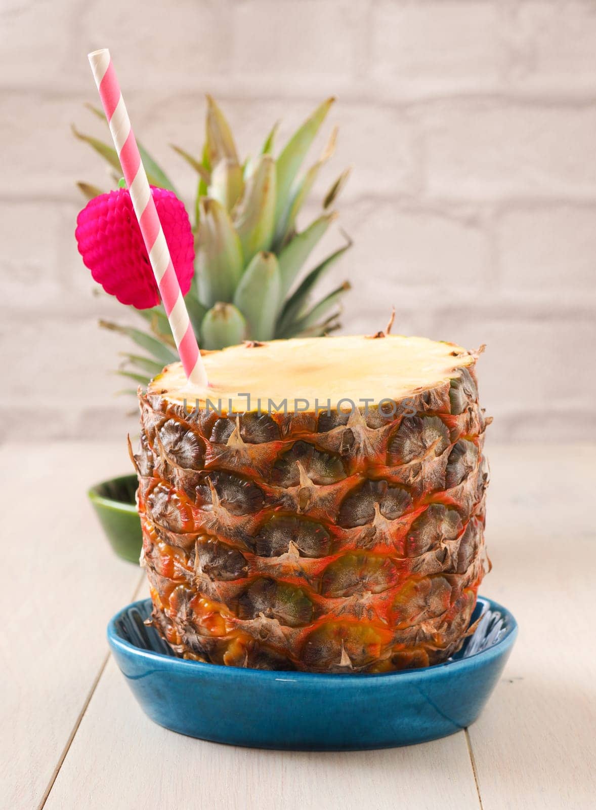 Fresh organic pineapple with a drinking straw on a wooden table