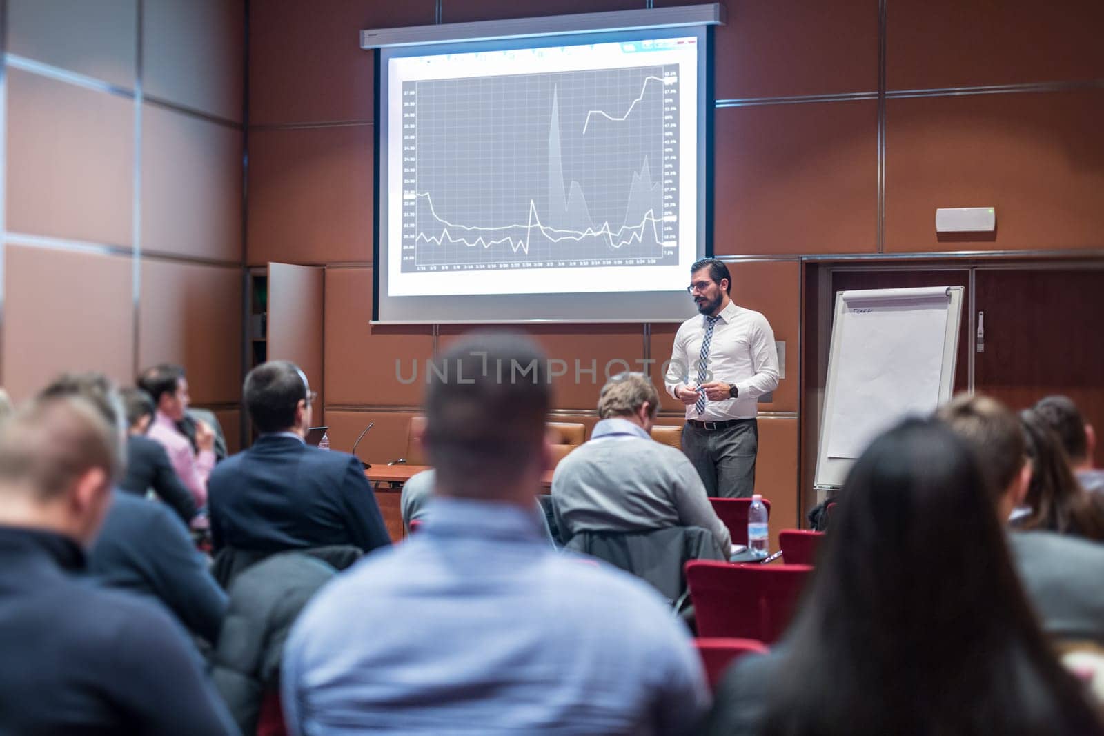 Public Speaker Giving a Talk at Business Meeting. Audience in the conference hall. Skilled coach answers questions of participants of business training. Business and Entrepreneurship concept.