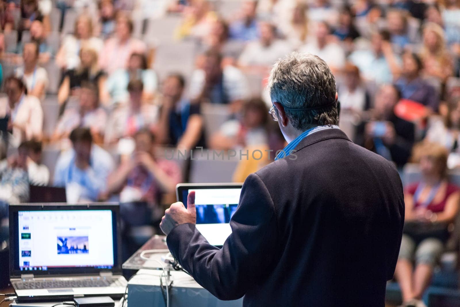 Speaker giving a talk on corporate business conference. Unrecognizable people in audience at conference hall. Business and Entrepreneurship event.