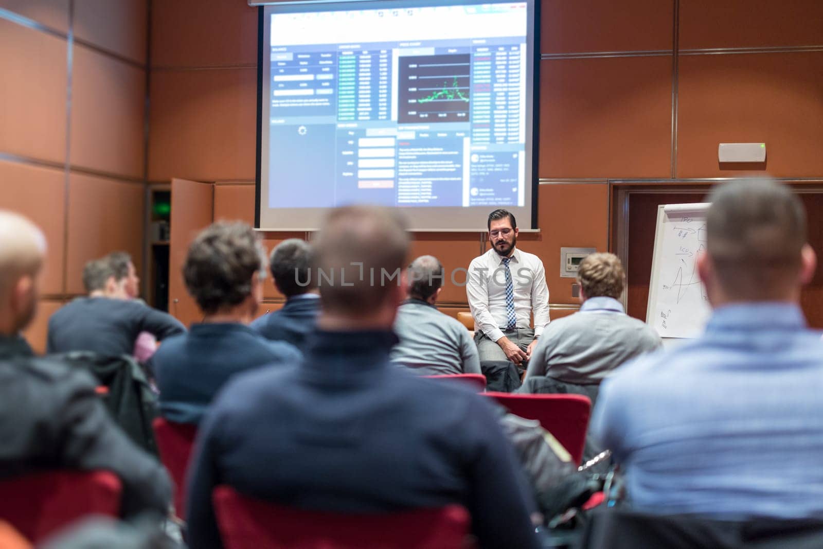 Public Speaker Giving a Talk at Business Meeting. Audience in the conference hall. Skilled coach asks questions to participants of business training. Business and Entrepreneurship concept.