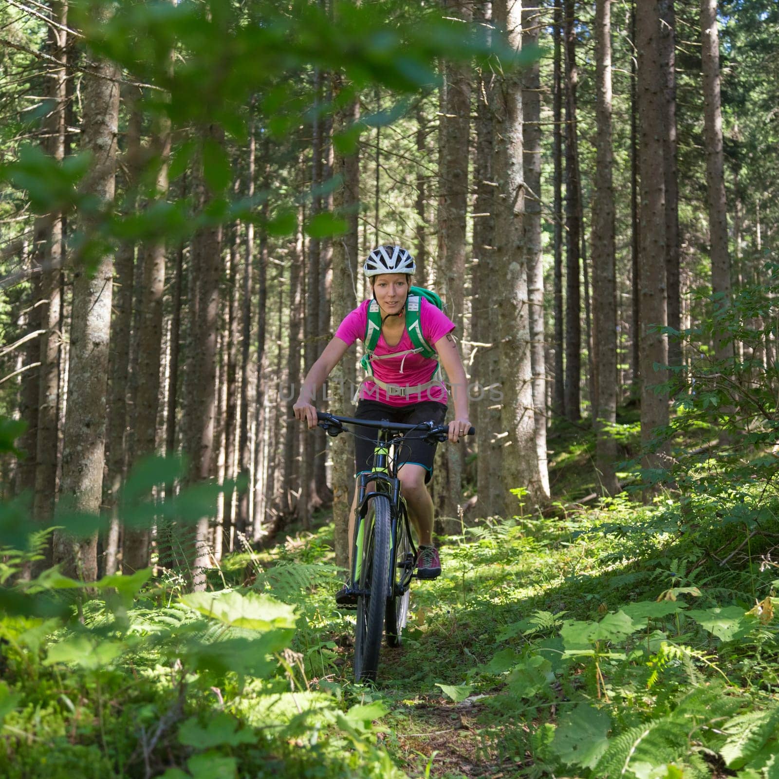 Active sporty woman riding mountain bike on demanding forest trail.