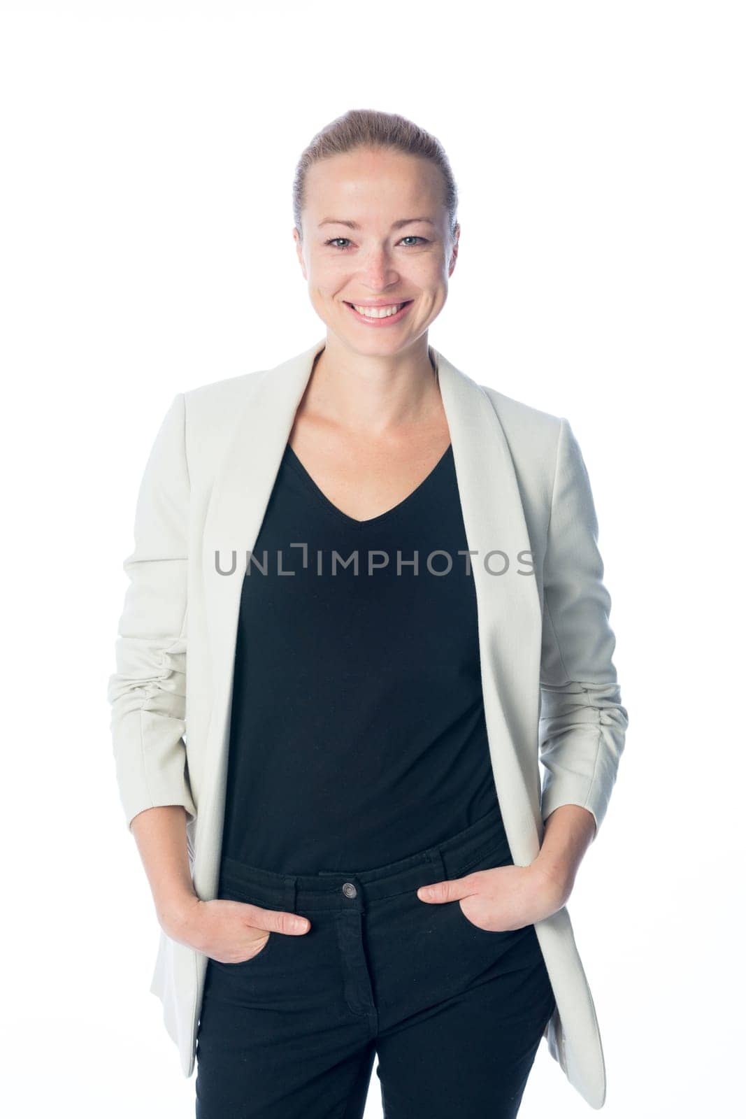 Full body portrait of casualy dressed,cheerful, beautiful, smart, young businesswoman in standing against white background hands in black jeans pockets.