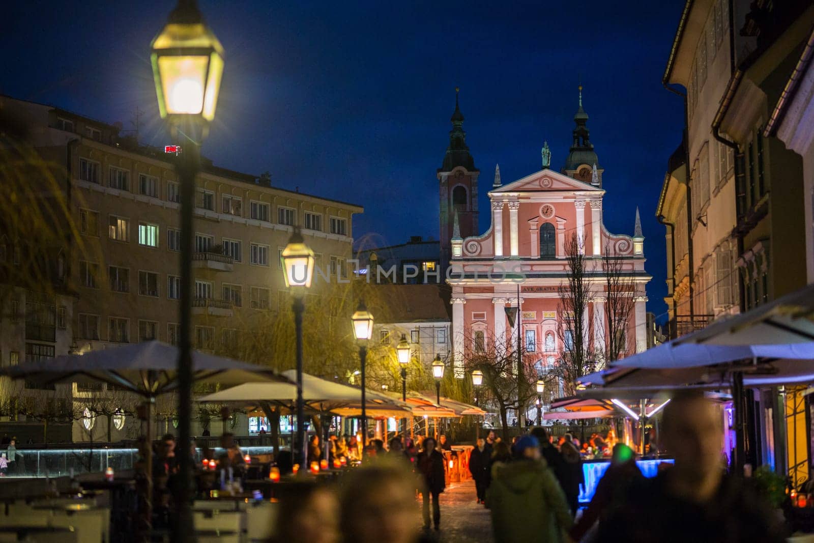 Romantic medieval Ljubljana's city center, the capital of Slovenia, Europe. Night life on the banks of river Ljubljanica, where many bars and restaurants take place. Franciscan Church in background.