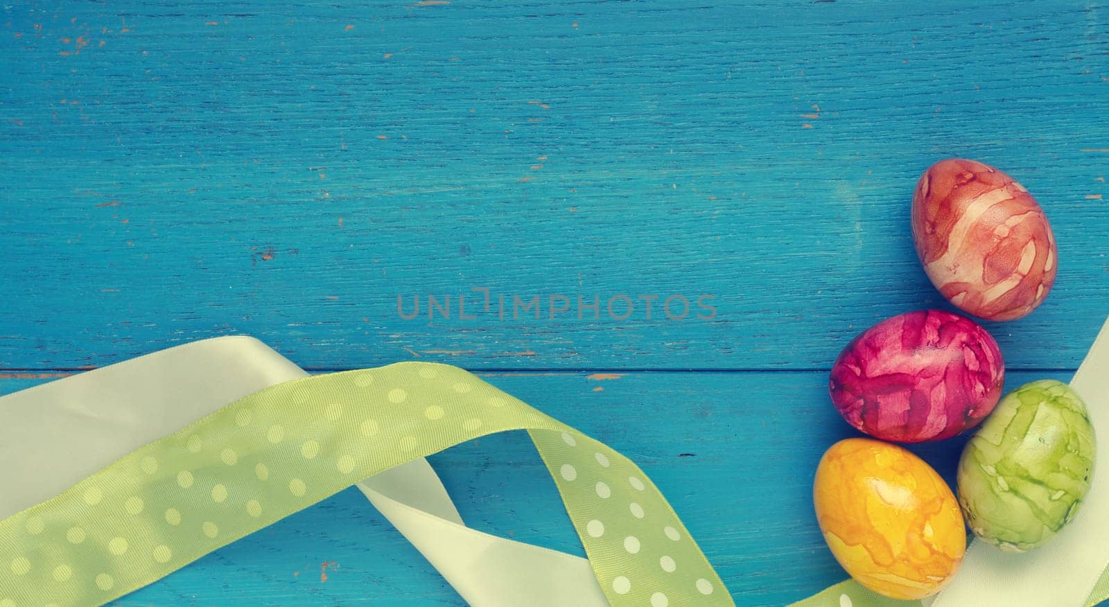 Colorful Easter eggs with decoration on a blue wooden background with space for text or image