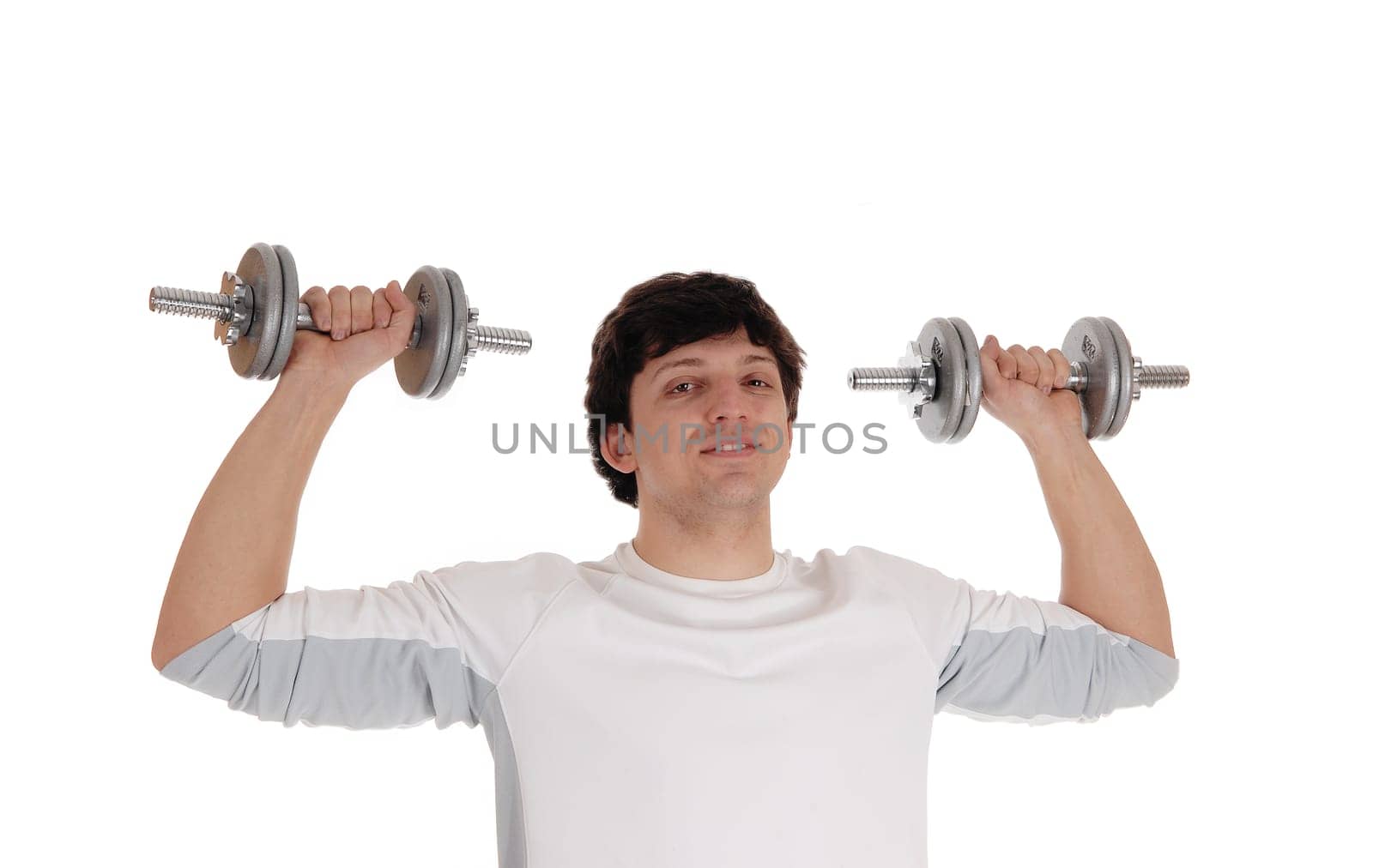 A closeup image of a young man lifting two dumbbells, looking into the camera.in a white t-shirt, isolated for white background.