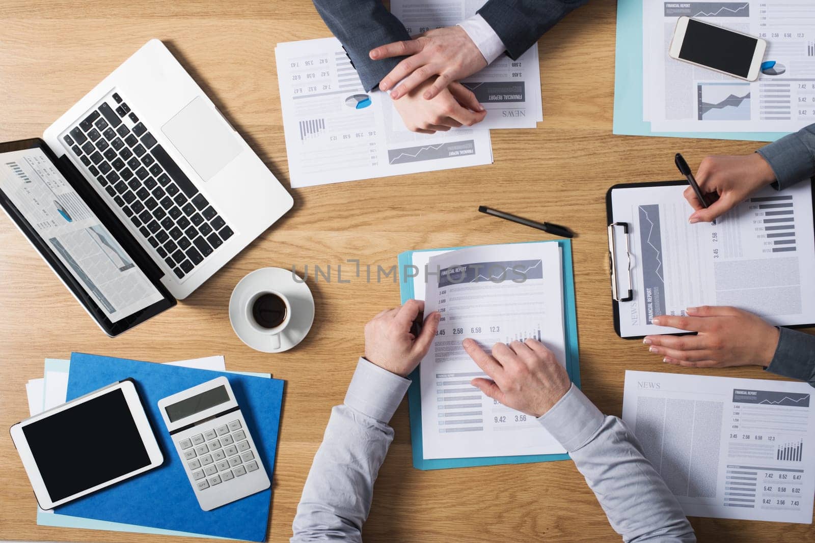 Business people team working together at office desk with laptop, tablet, financial paperwork and reports, top view