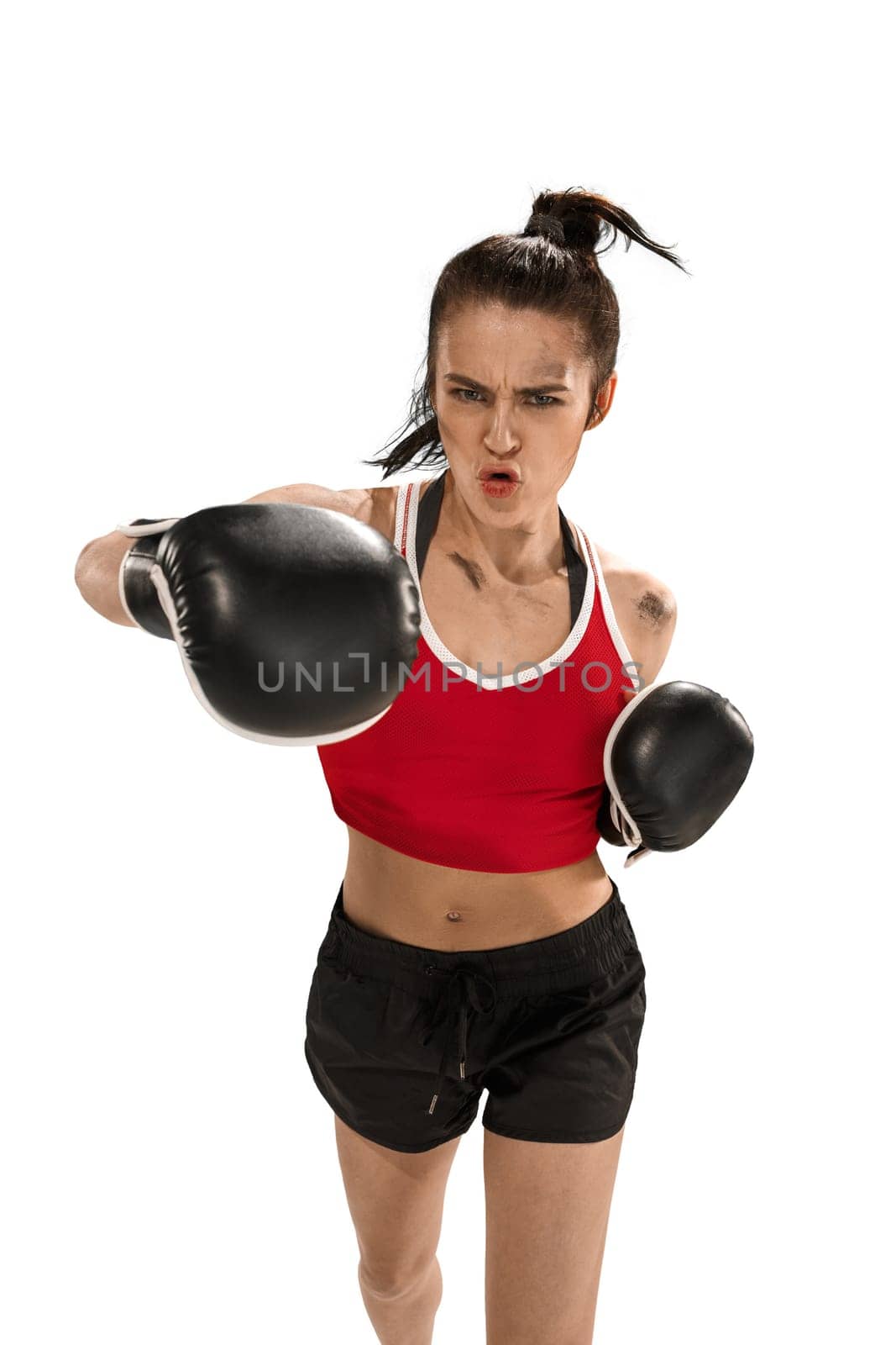 Young active beautiful woman with the black boxing gloves boxing at studio isolated on white background. Fitness, boxing concept. Female boxer. Human emotions. Caucasian model. head blow energy