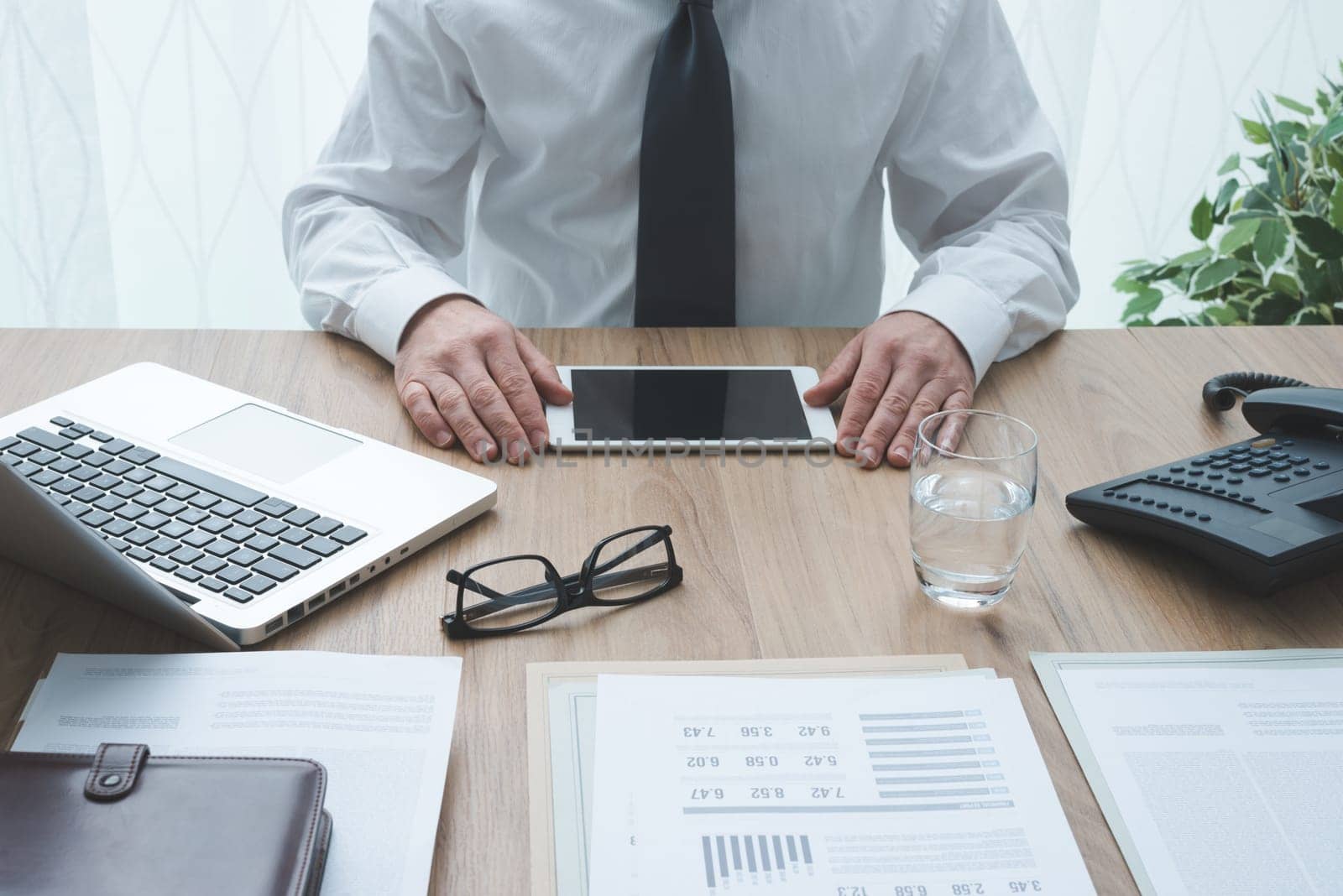 Professional corporate businessman working at office desk and using a digital tablet