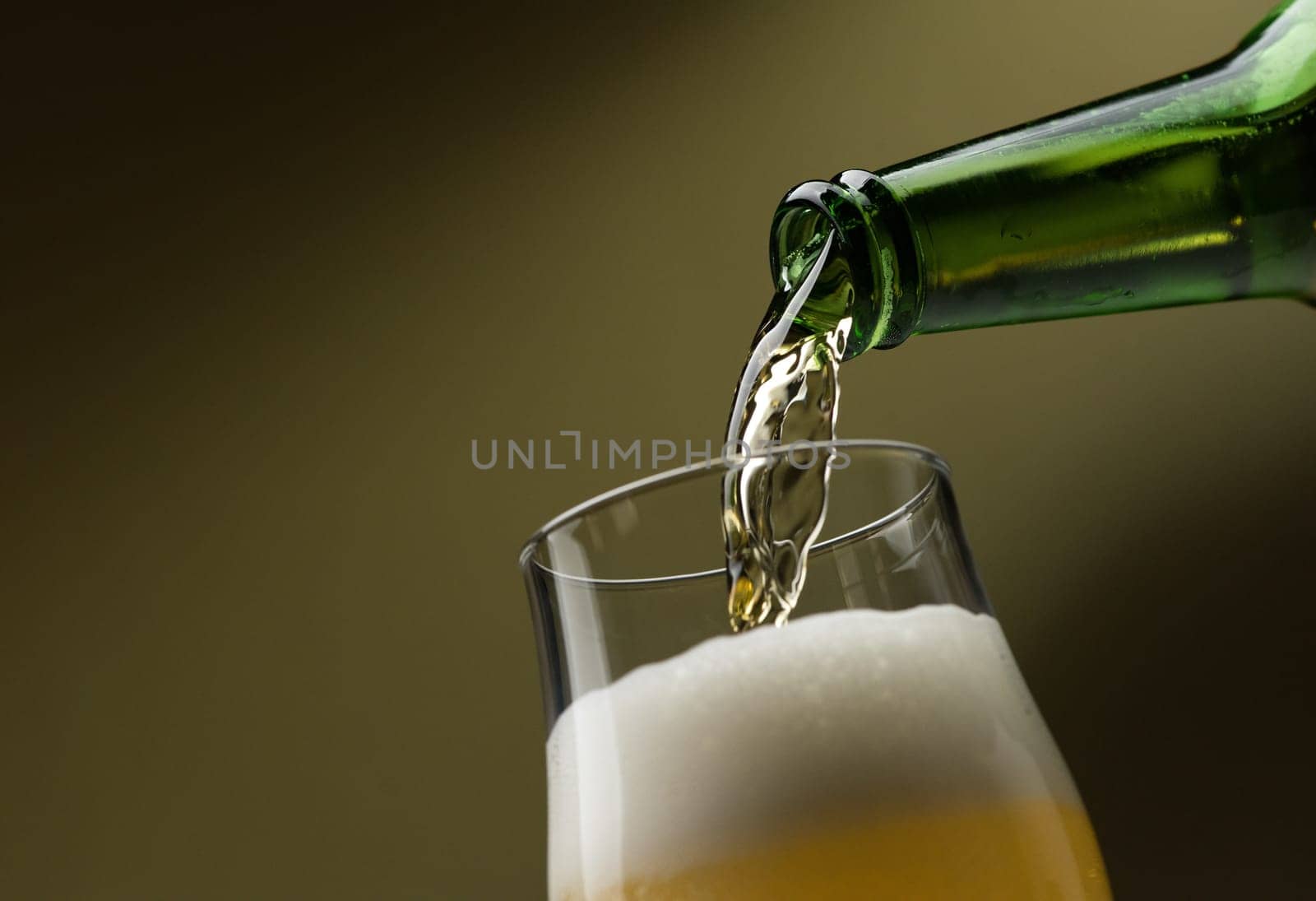 Pouring fresh beer from a bottle into a glass, alcoholic drinks and celebration concept