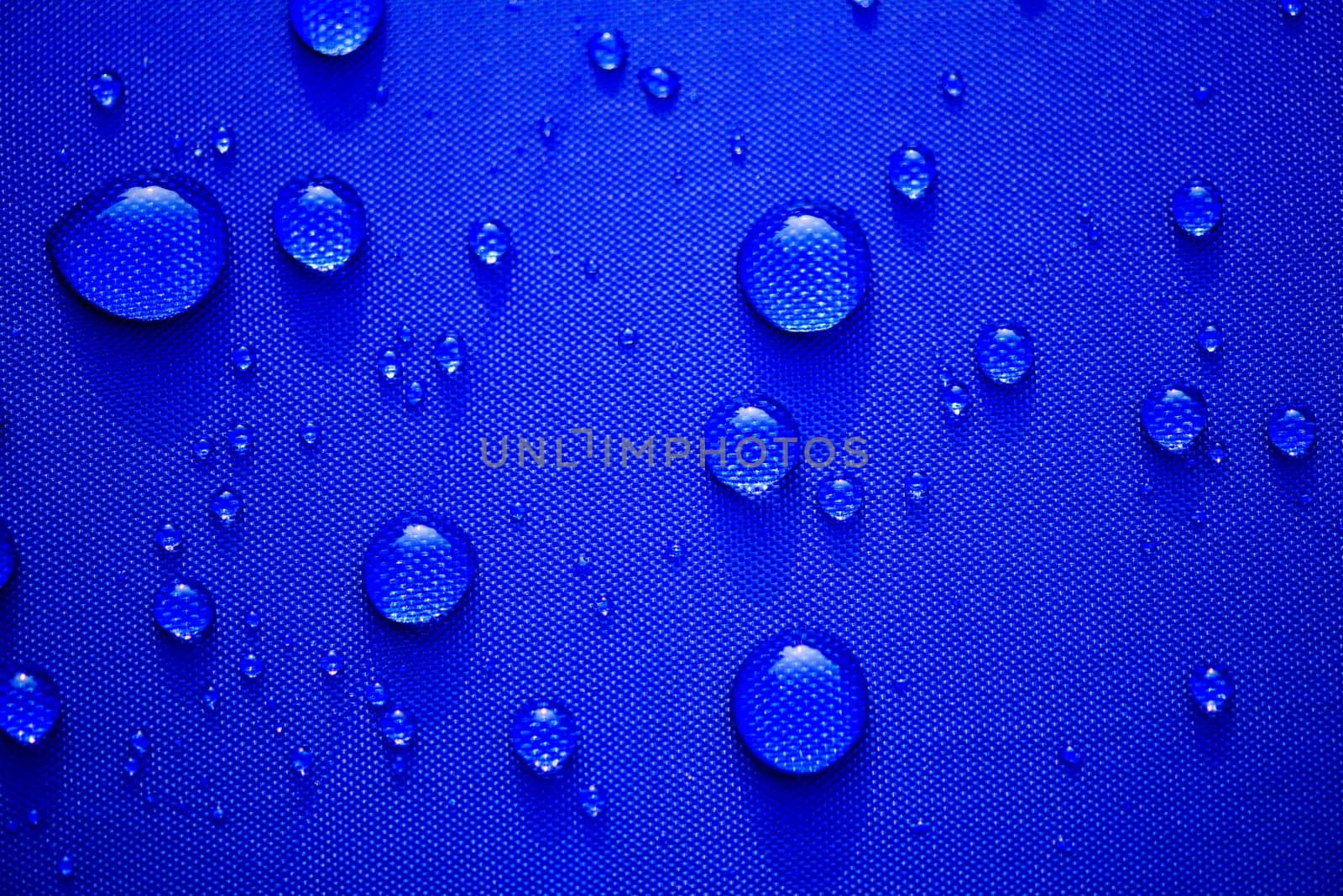 Close up Water drops pattern over a blue waterproof cloth background. World Water Day concept.