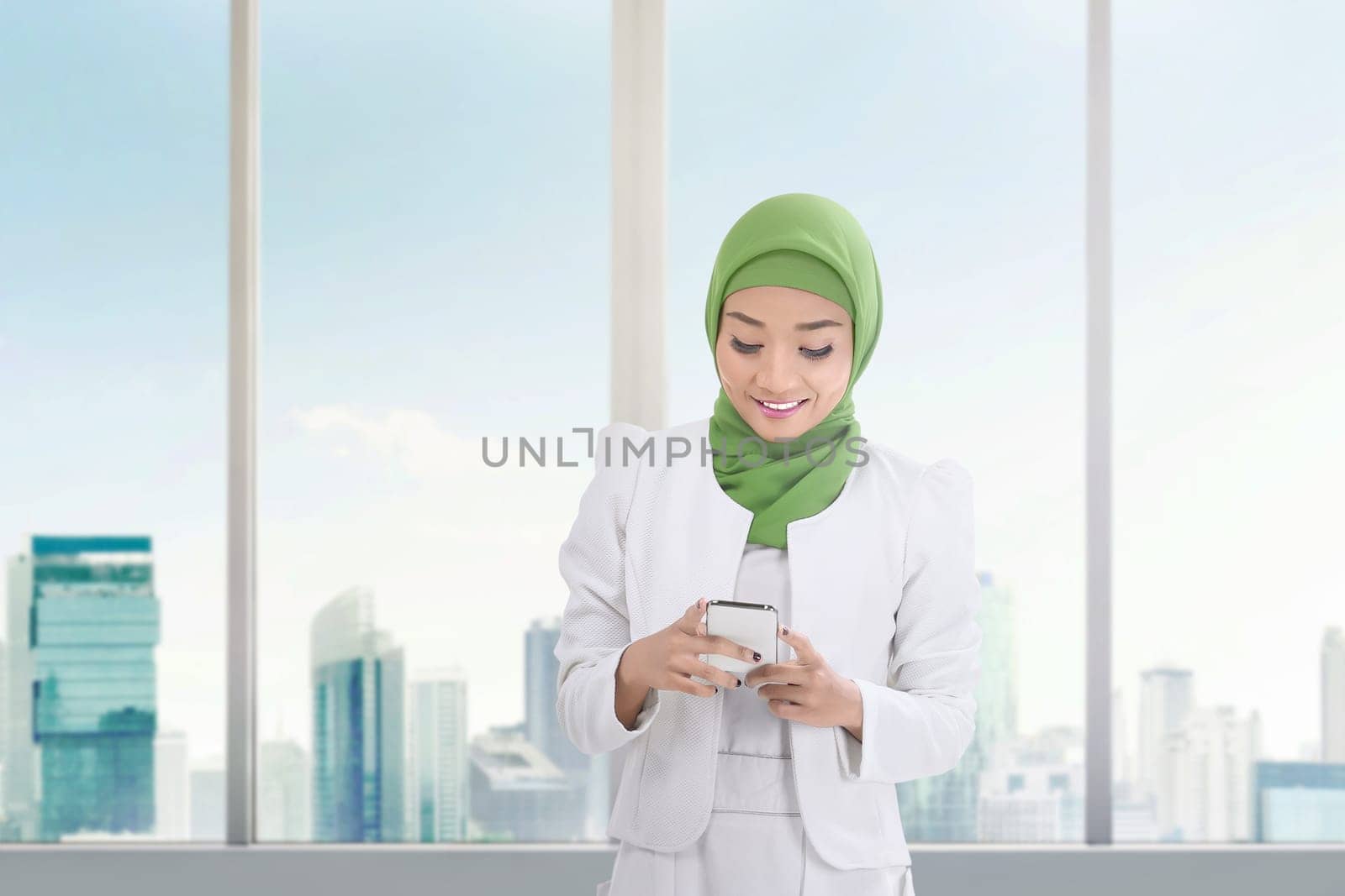Beautiful asian muslim woman with mobile phone inside the building