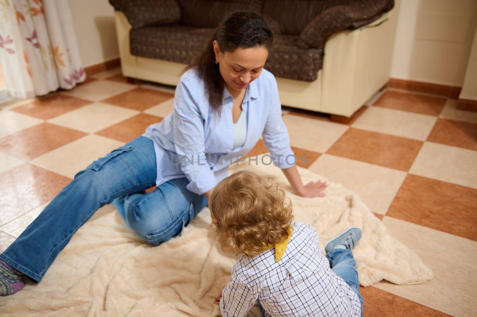 Mother and child sitting on a cozy floor bonding indoors, surrounded by comfortable decor, embodying maternity sentiments and shared joy.