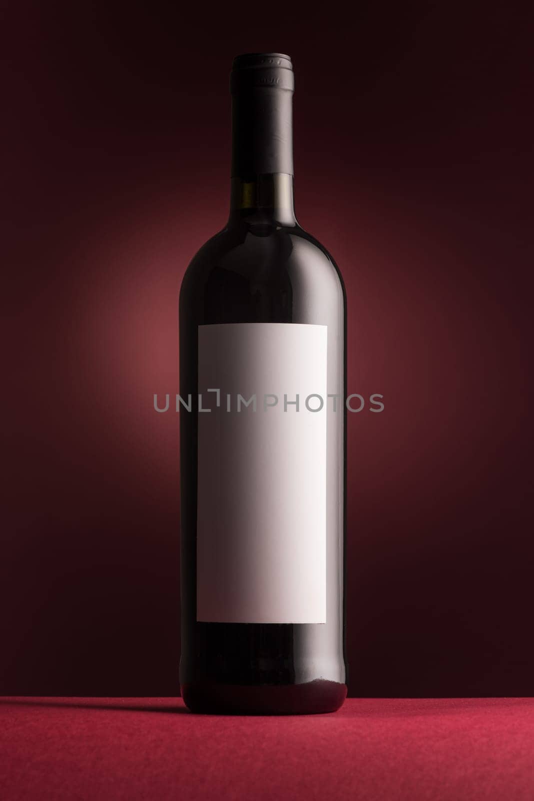 Excellent red wine bottle with blank label on red background