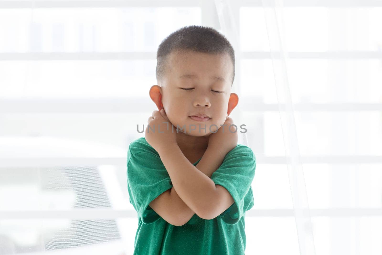 Young child at home. Playful Asian boy get punished by pulling ears.