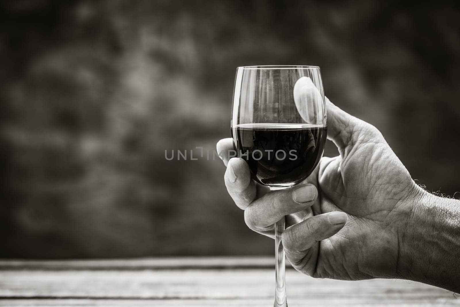 Senior wine expert tasting a glass of red wine in the cellar, hand close up, wine tradition and culture concept