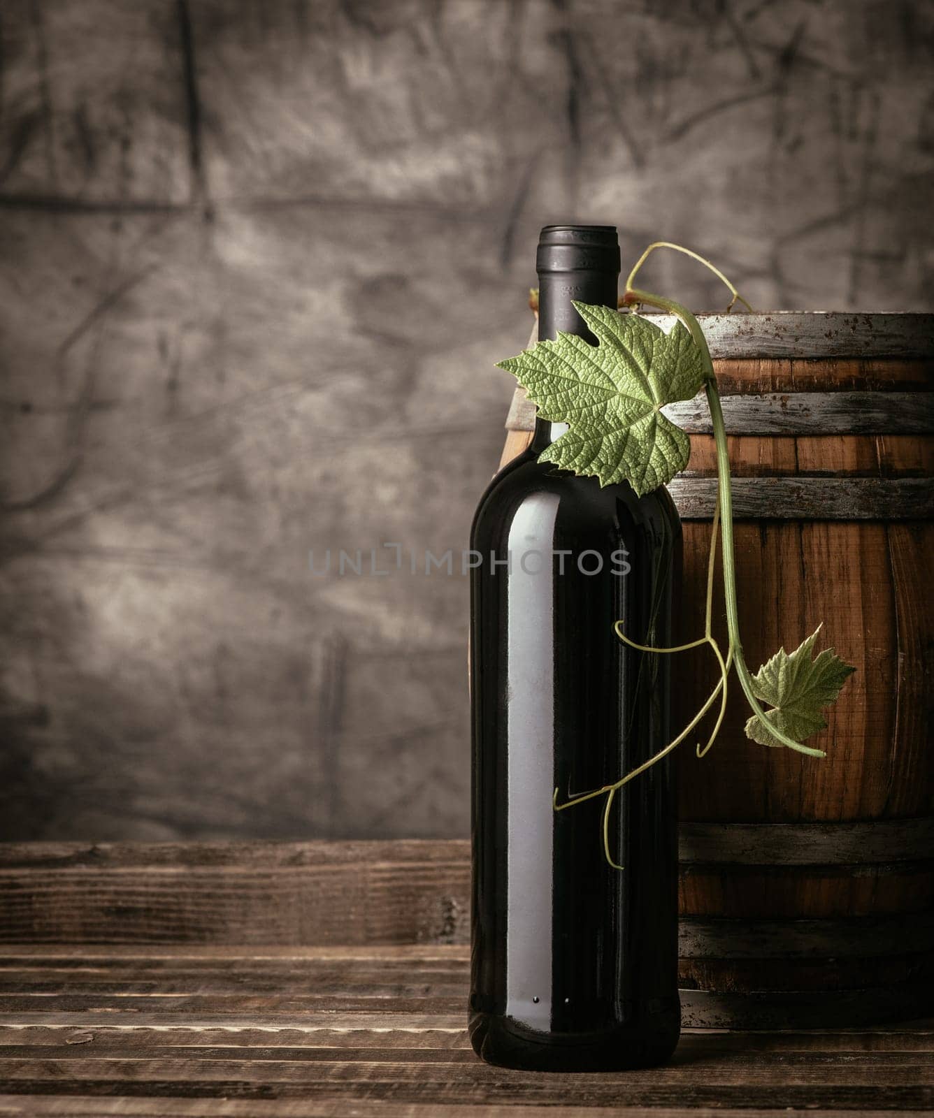 Red wine bottle, vine leaf and wooden barrel in the cellar, traditional wine making and tasting concept