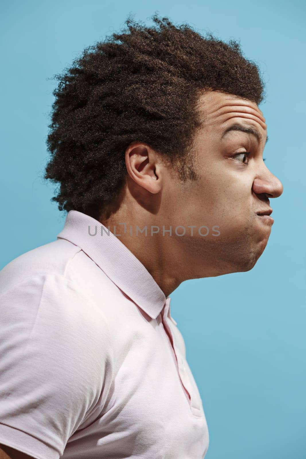 Screaming, hate, rage. Crying emotional angry afro man screaming on blue studio background. Emotional, young face. male half-length portrait. Human emotions, facial expression concept. Trendy colors