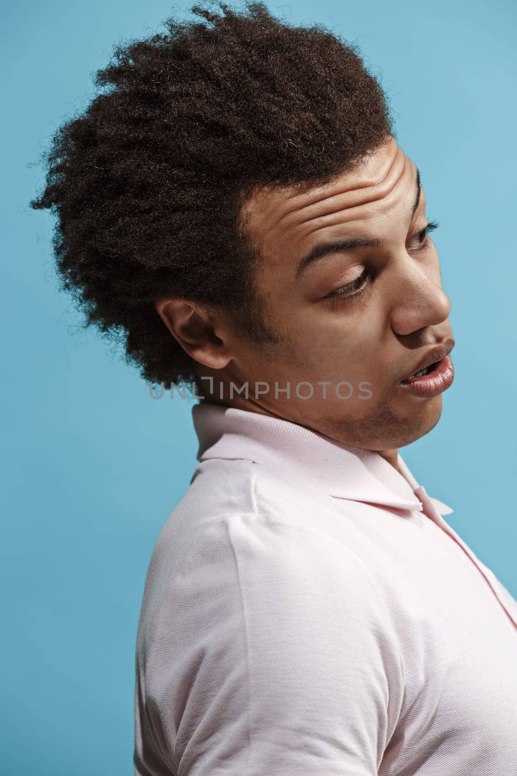 Argue, arguing concept. Beautiful male half-length portrait isolated on blue studio backgroud. Young emotional surprised afro man Human emotions, facial expression concept. Profile view