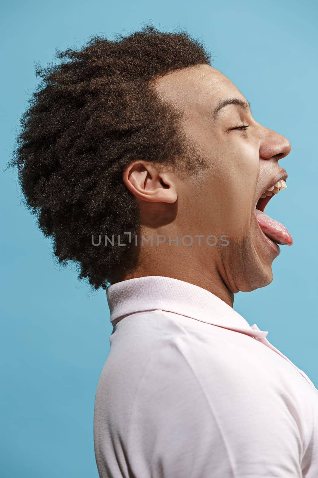 Happy business man standing and smiling isolated on blue studio background. Beautiful male half-length portrait. Young emotional man. The human emotions, facial expression concept. Profile view.