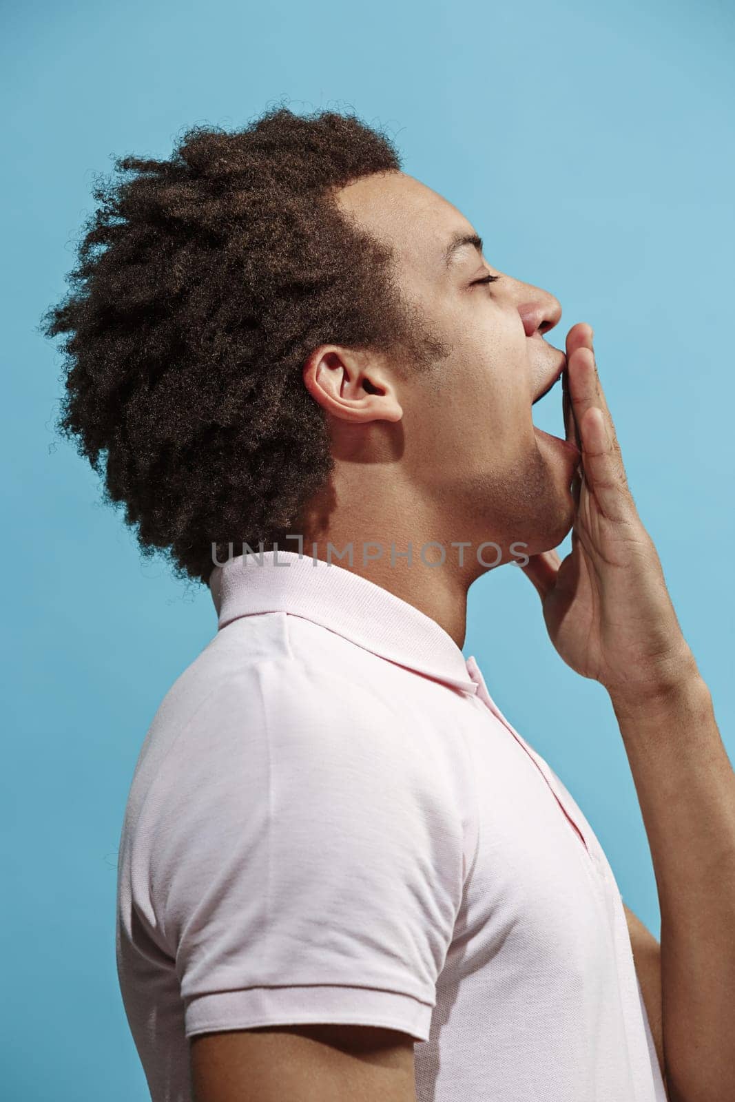 I am tired of everything. Sad man. Boring, dull, tedious concept. Young afro emotional man. Human emotions, facial expression concept. Studio Isolated on trendy blue background. Profile