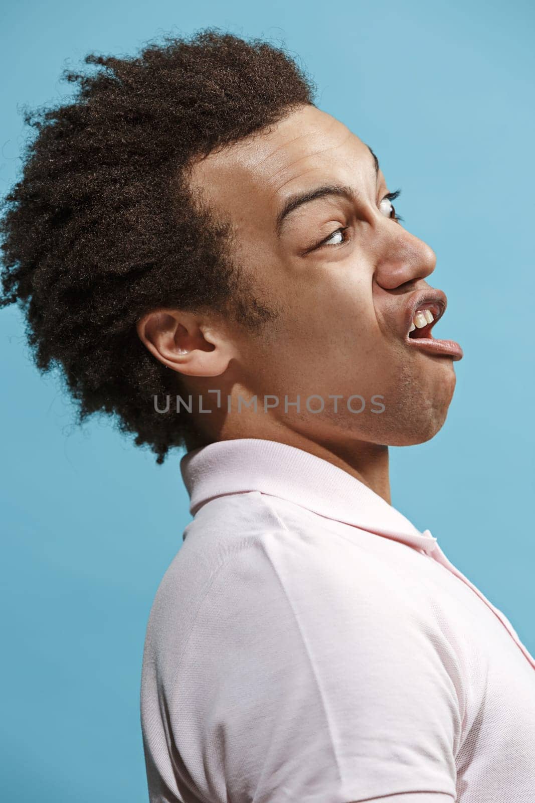 Argue, arguing concept. Beautiful male half-length portrait isolated on blue studio backgroud. Young emotional surprised man looking at camera. Human emotions, facial expression concept. Profile view