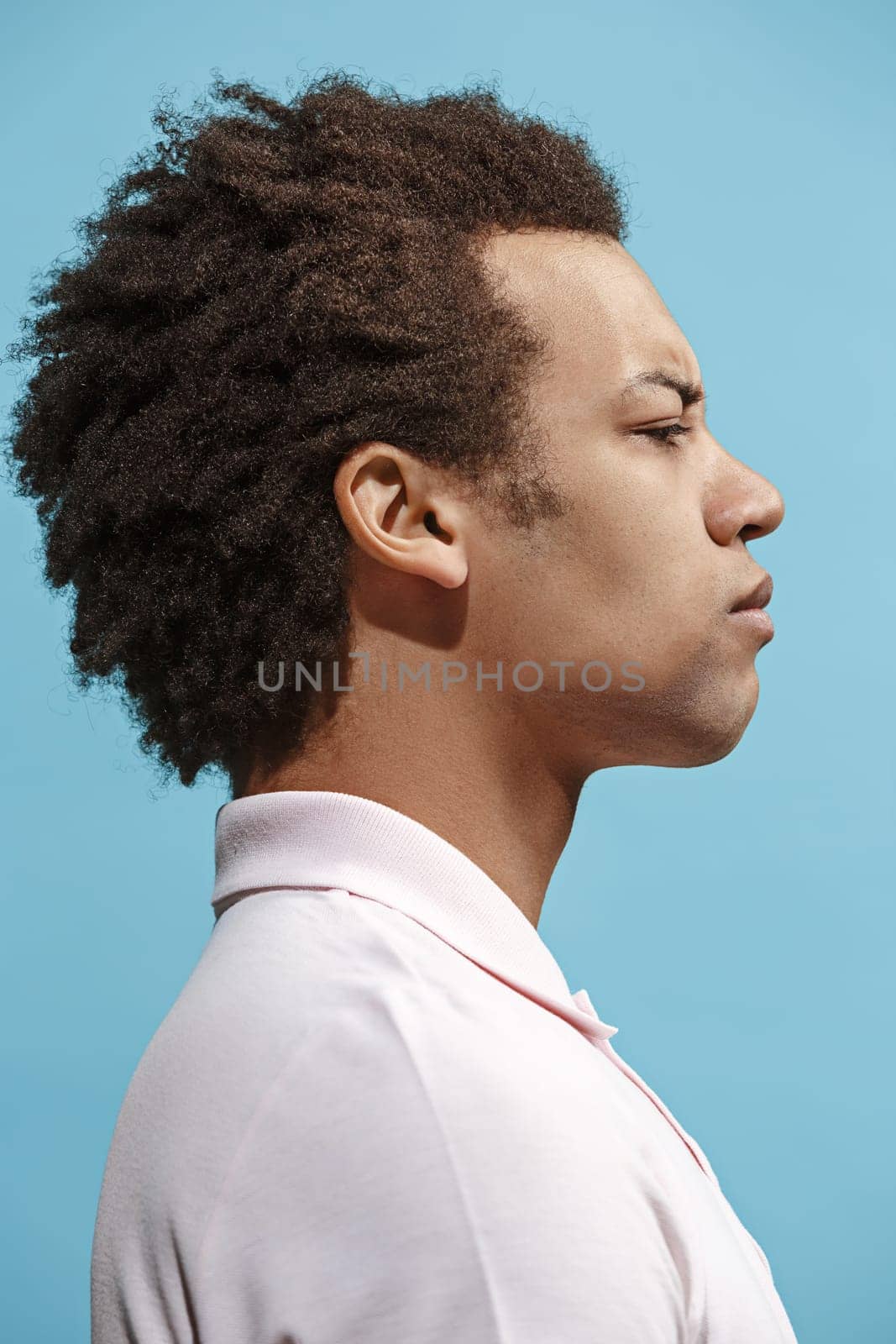 I am tired of everything. Sad man. Boring, dull, tedious concept. Young afro emotional man. Human emotions, facial expression concept. Studio Isolated on trendy blue background. Profile