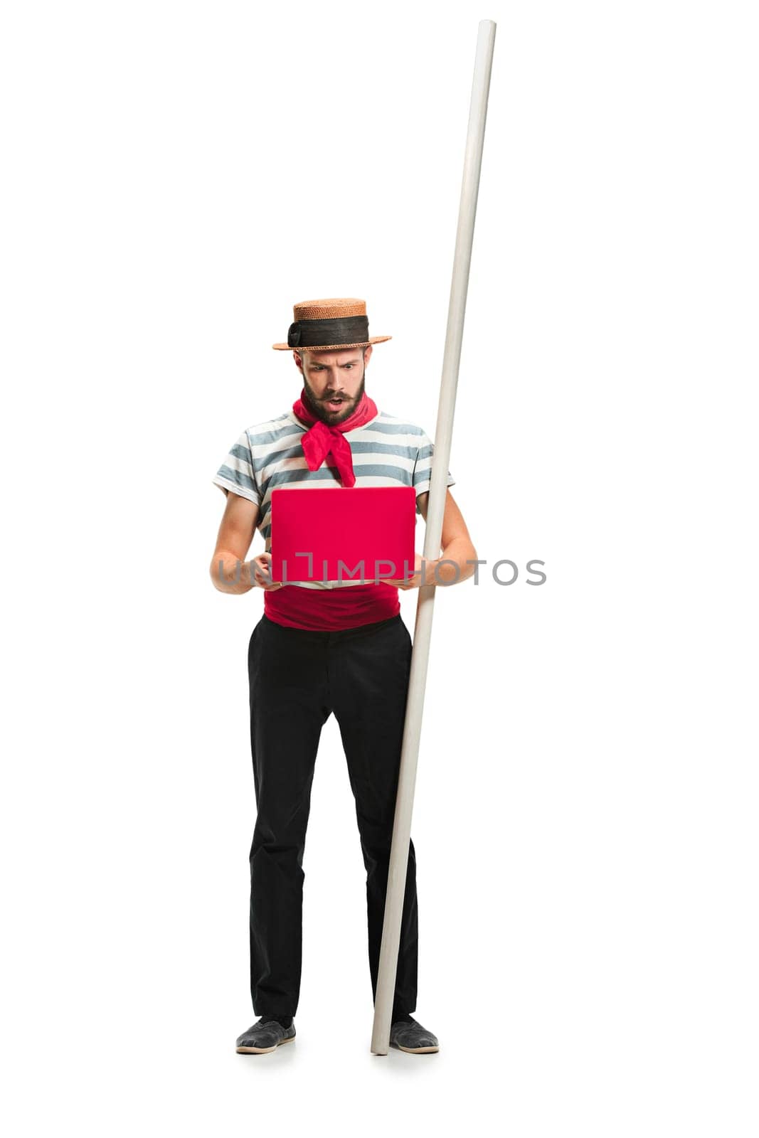Caucasian funny bearded man in traditional gondolier costume and hat with paddle standing with mobile phone at studio isolated on white background. young man. Human emotions, facial expression concept