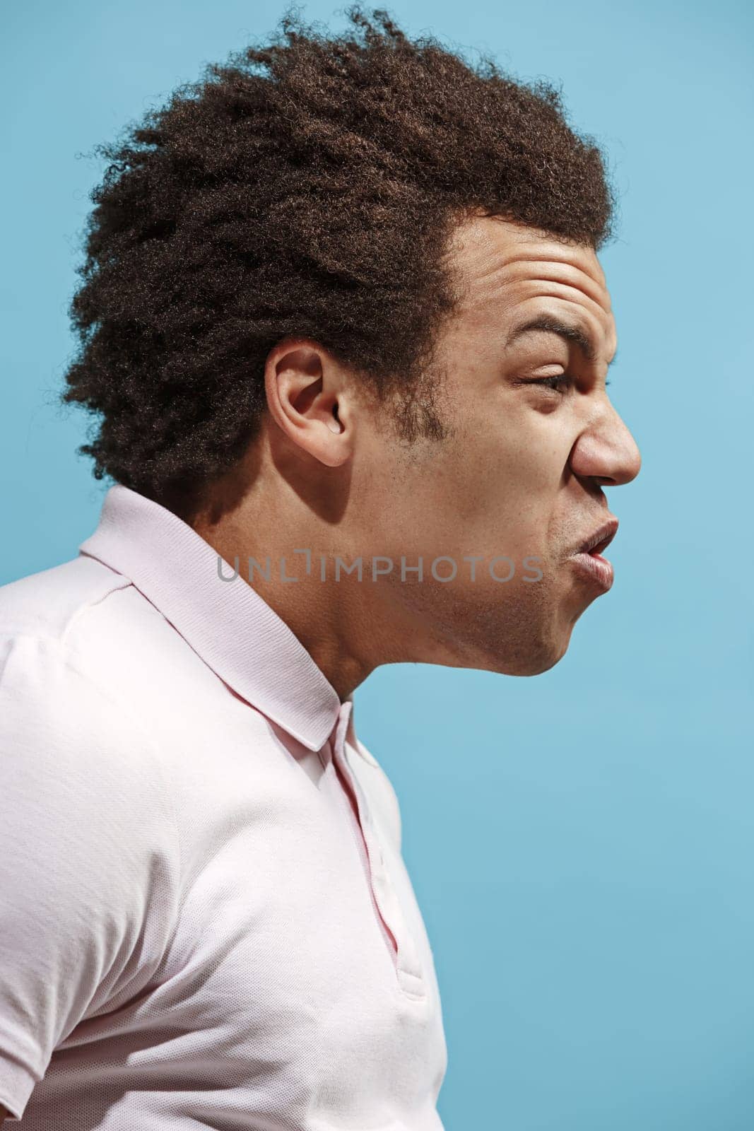 Screaming, hate, rage. Crying emotional angry afro man screaming on blue studio background. Emotional, young face. male half-length portrait. Human emotions, facial expression concept. Trendy colors