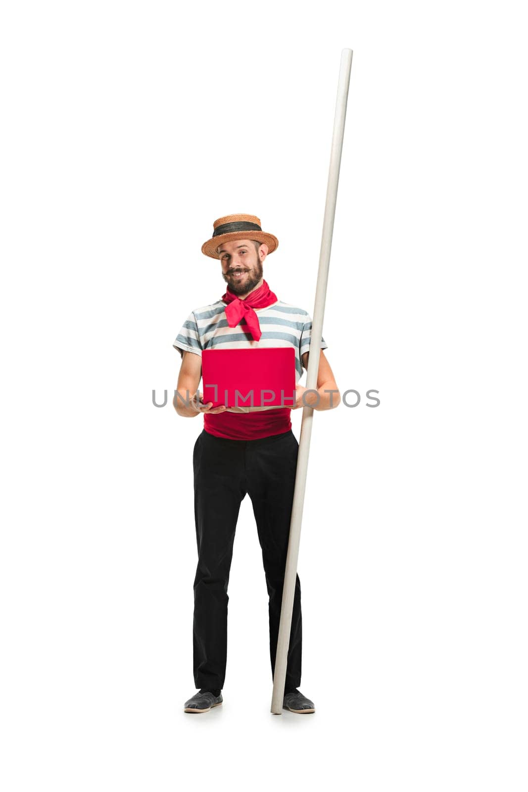 Caucasian funny bearded man in traditional gondolier costume and hat with paddle standing with mobile phone at studio isolated on white background. young man. Human emotions, facial expression concept