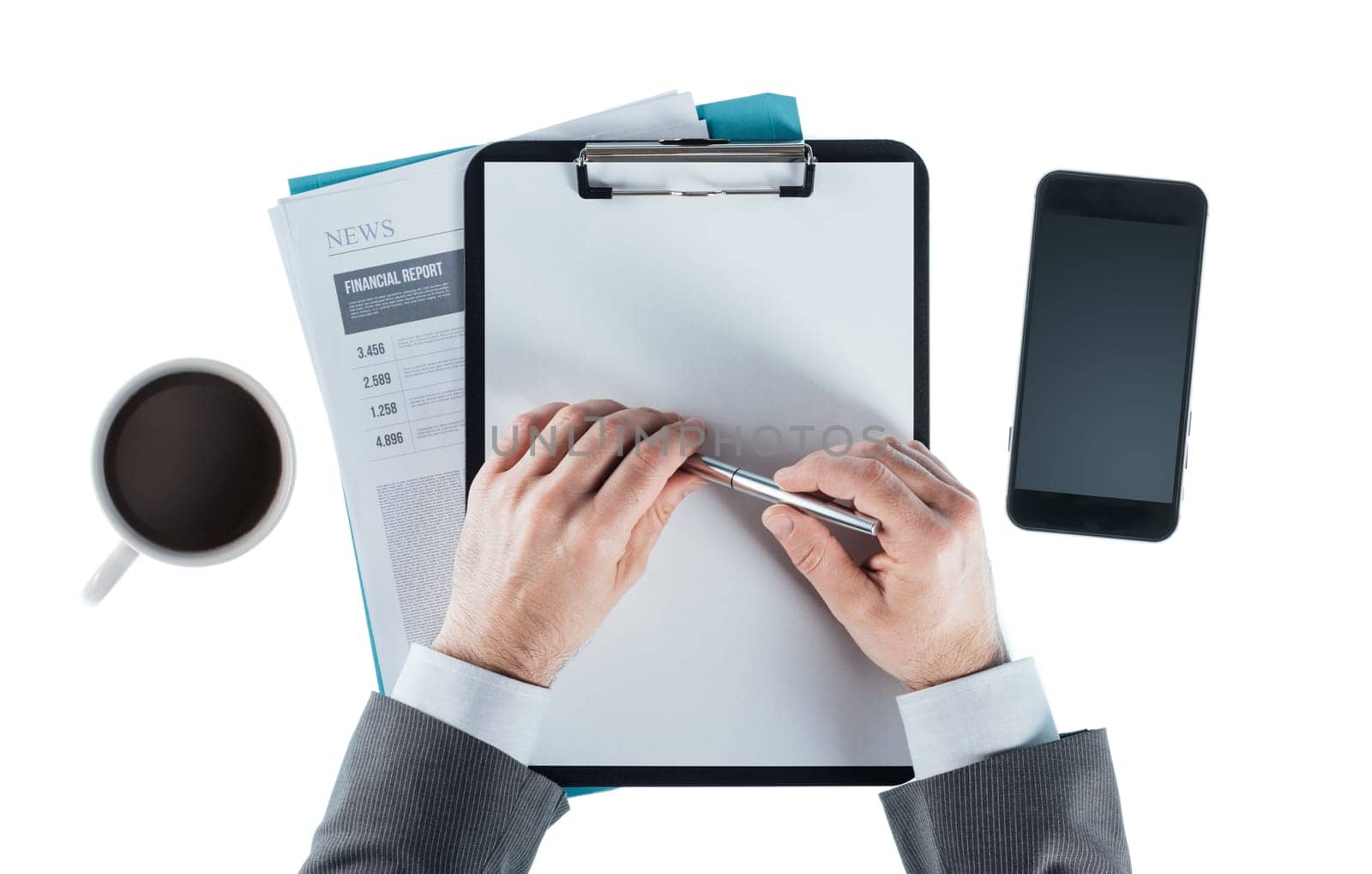 Businessman at desk holding a pen with clipboard, smartphone and coffee