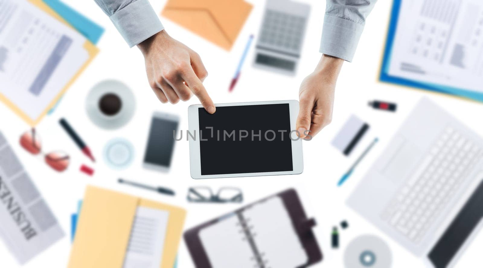 Businessman using a digital touch screen tablet, hands close up top view, desktop on background