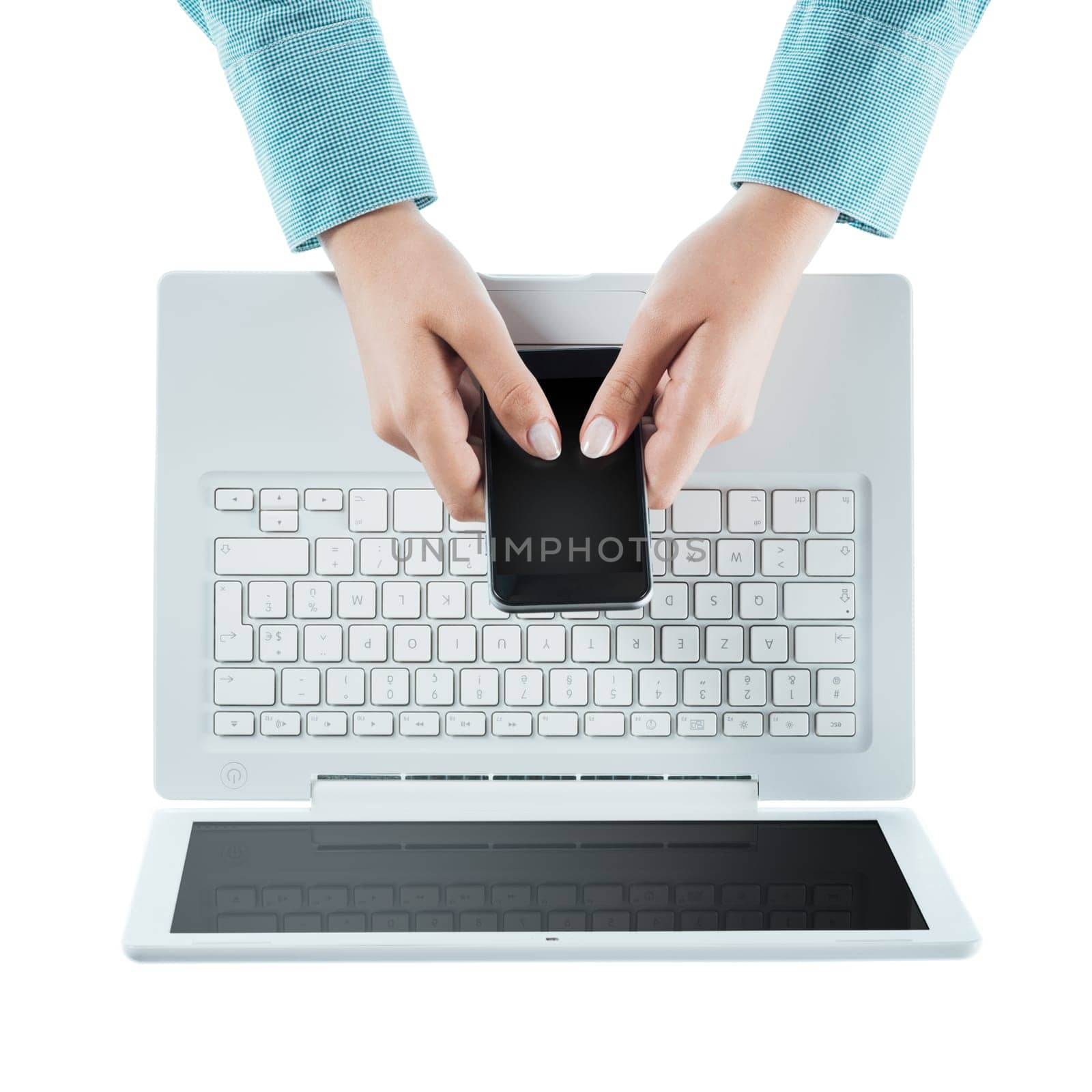 Woman using a touch screen smart phone and a laptop on white background, hands close up, top view