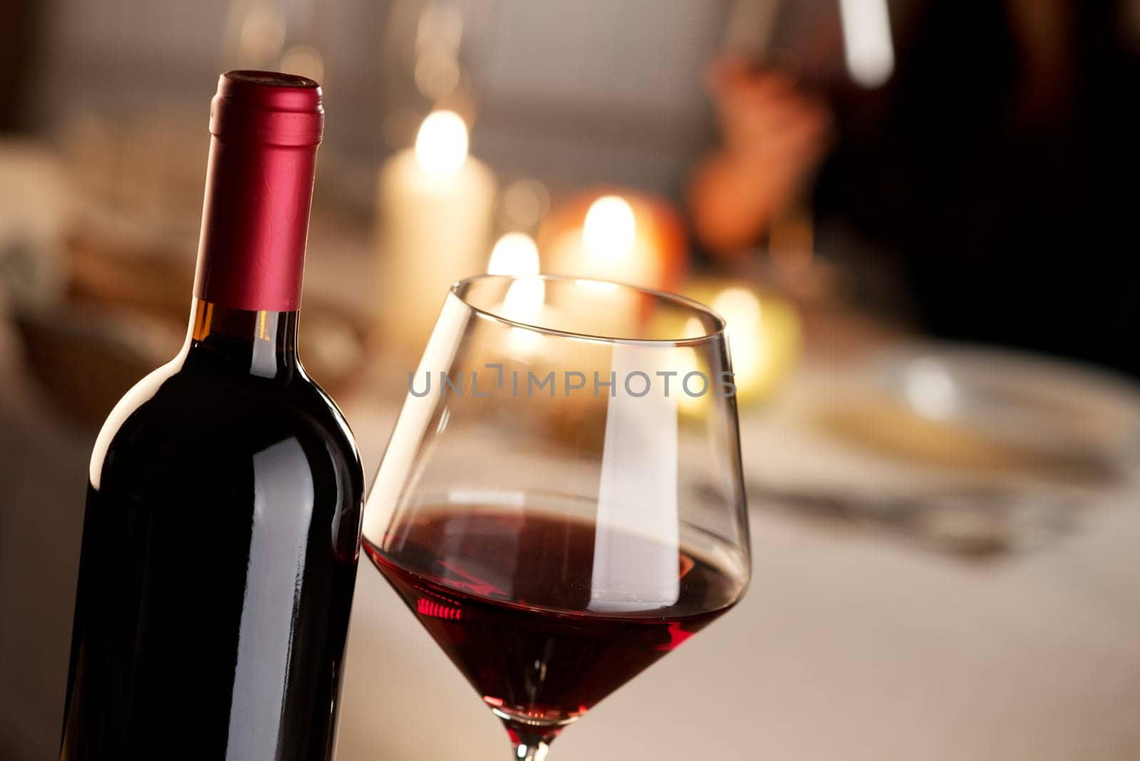 Bottle and glass of red wine with restaurant on background.