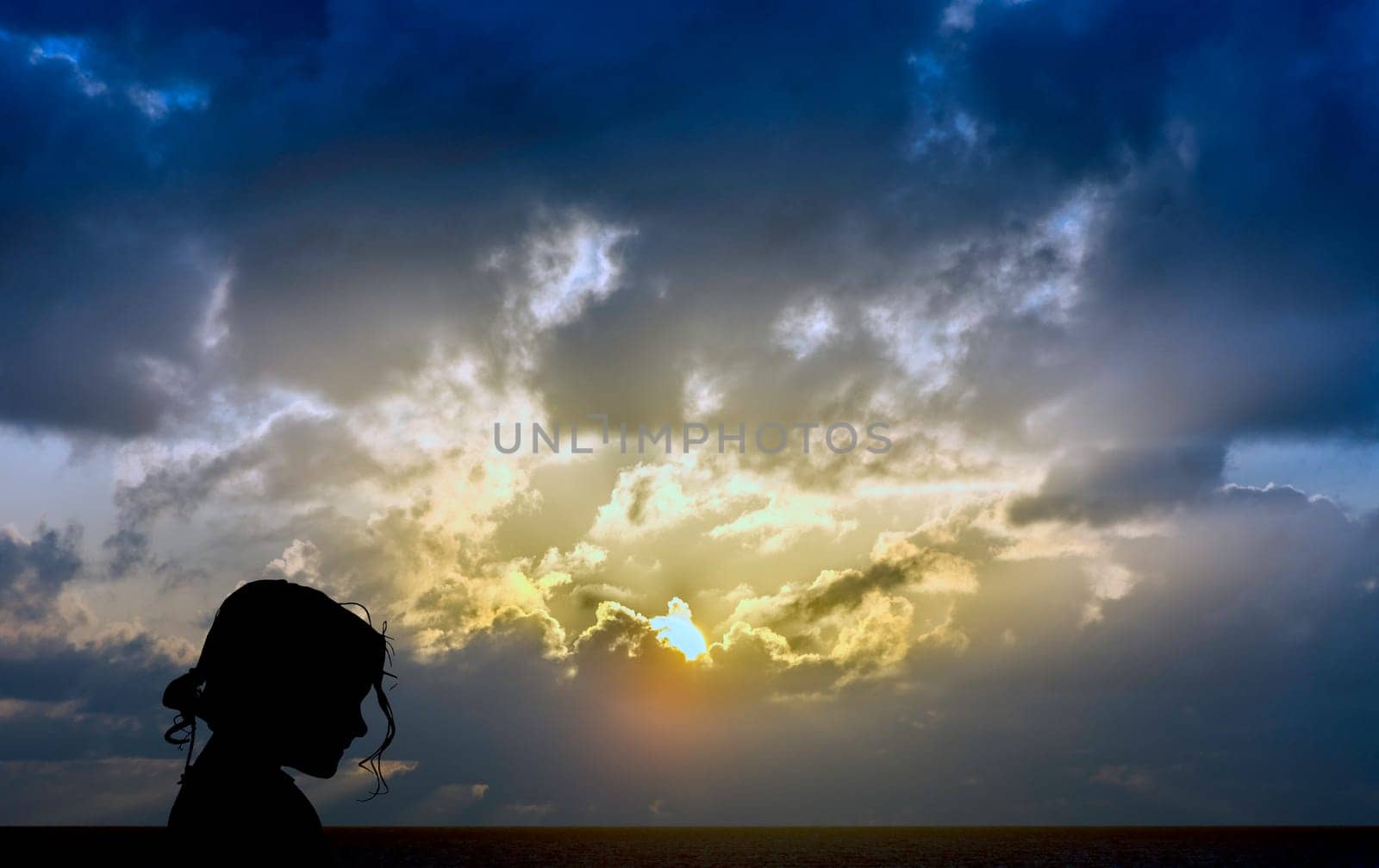 Silhouette of a young girl with dramatic sunrise over the ocean in background - Los Cocoteros, Lanzarote, Canary Islands, Spain