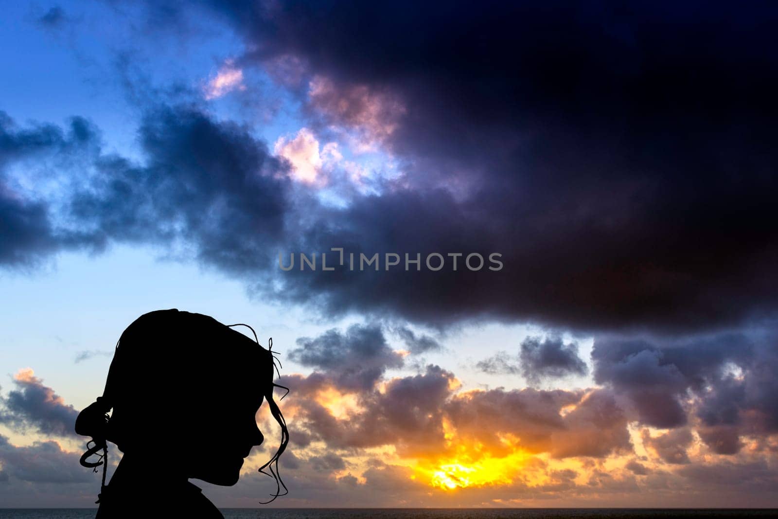 Silhouette of a young girl with dramatic sunrise over the ocean in background - Los Cocoteros, Lanzarote, Canary Islands, Spain