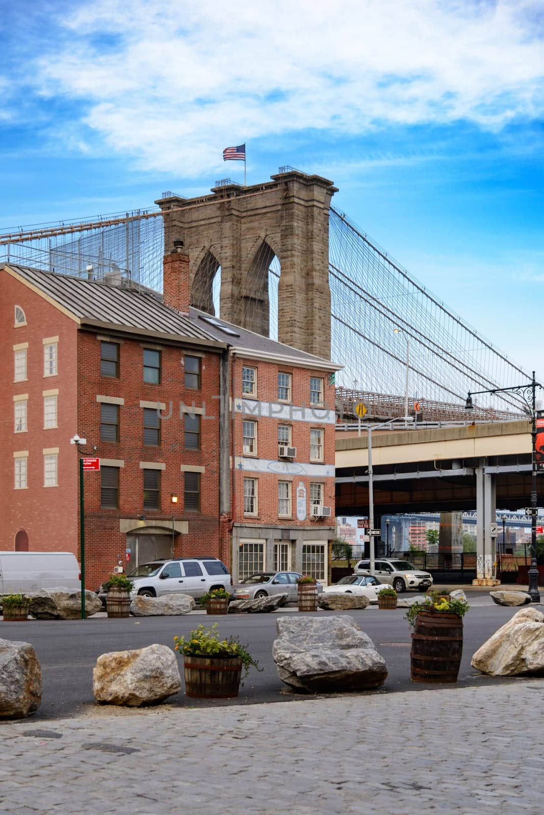 Brooklyn Bridge, New York, United States - June 08, 2015: People walk and while other tourists observe, from the bridge, the Manhattan skyline.