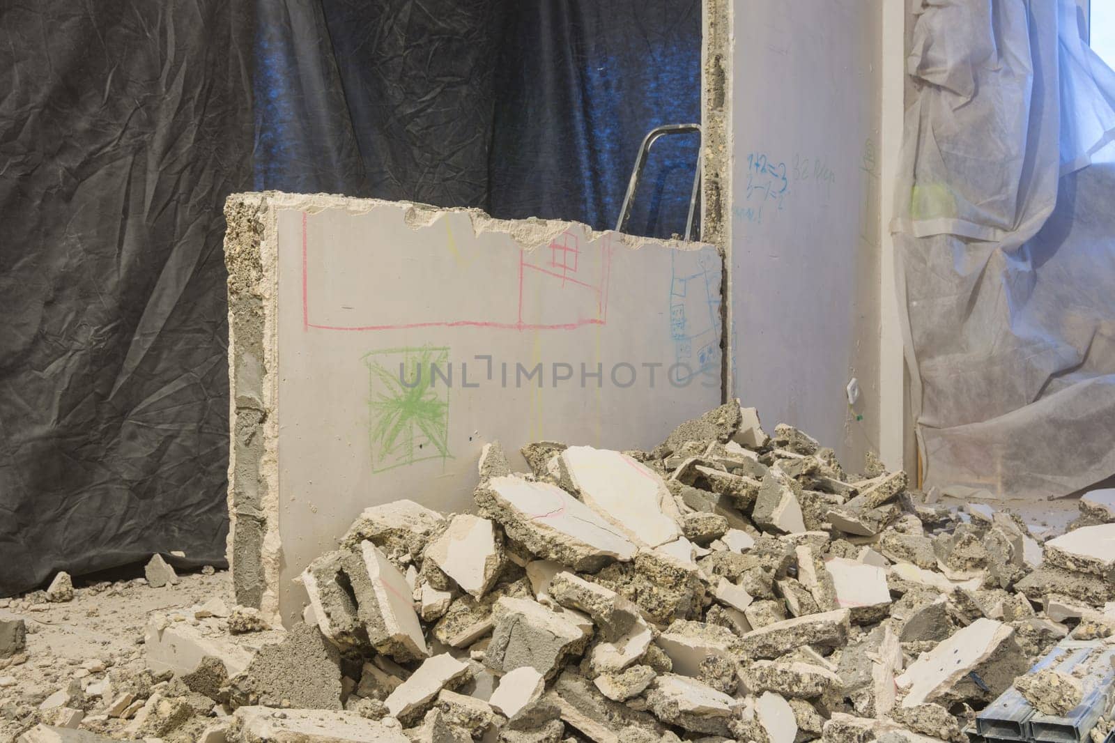 Broken pieces of the wall lie near the wall being dismantled