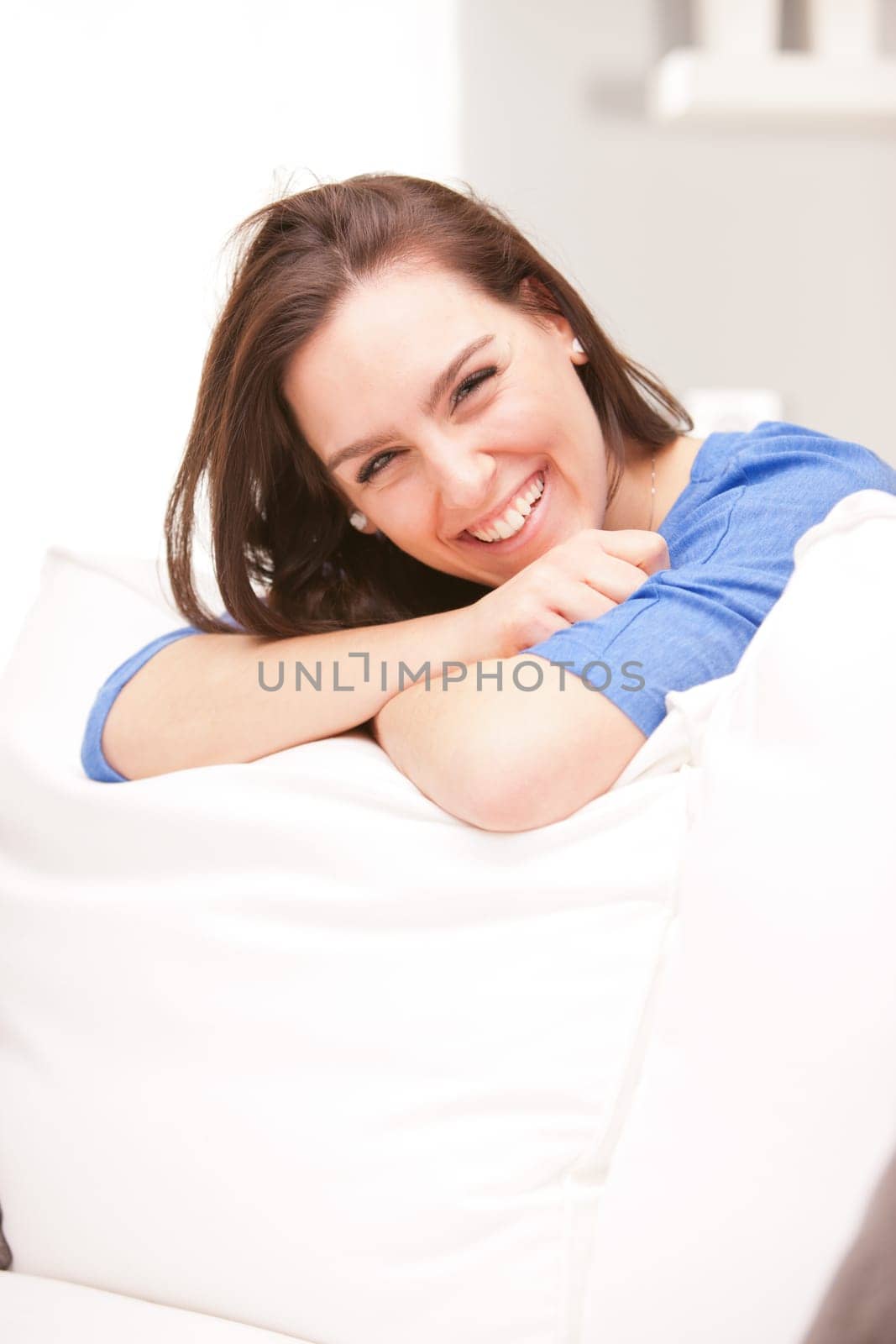 Happy smiling woman in her white living room thinking about how much she's lucky and successful