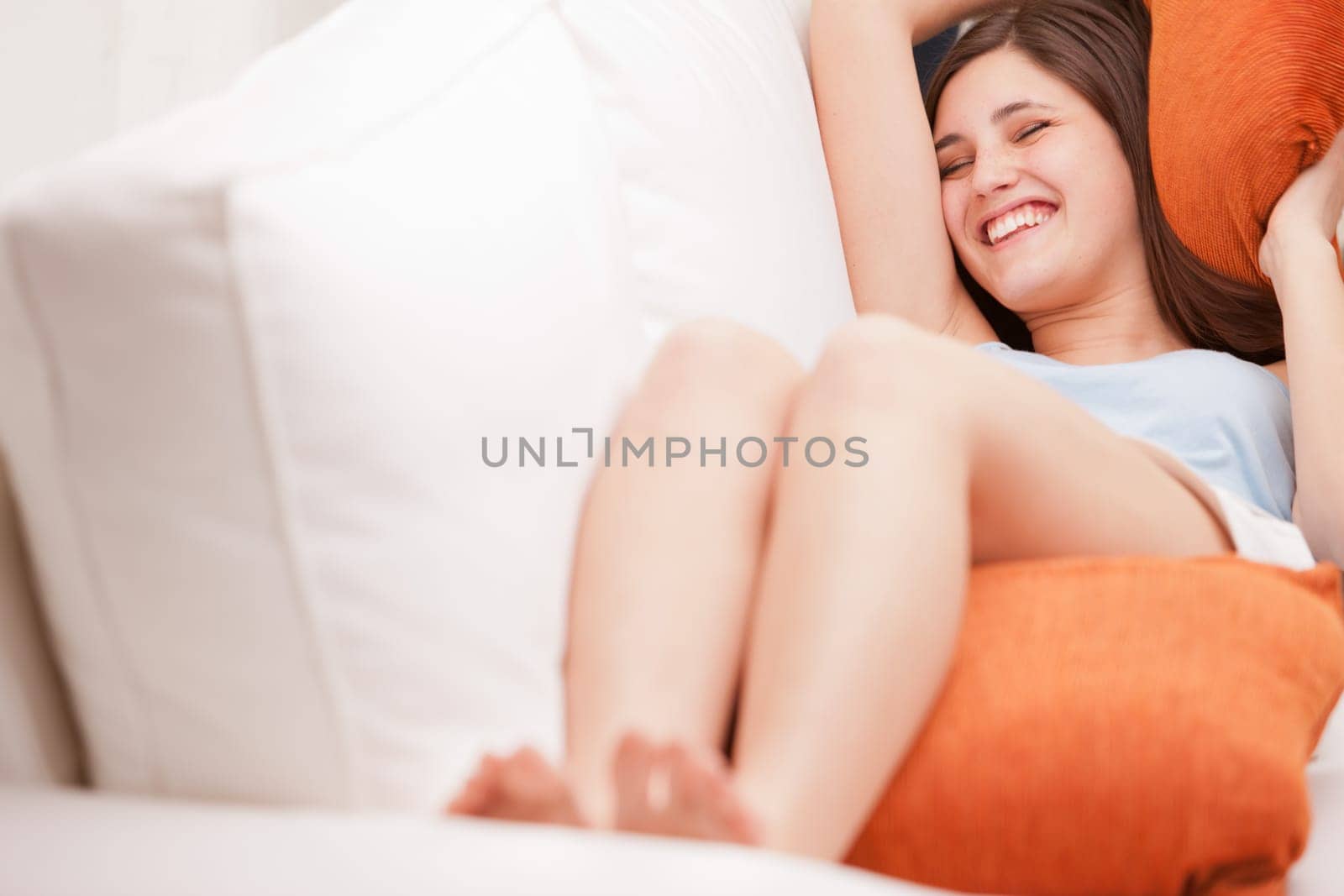 young woman laughing while relaxing on her sofa in her living room