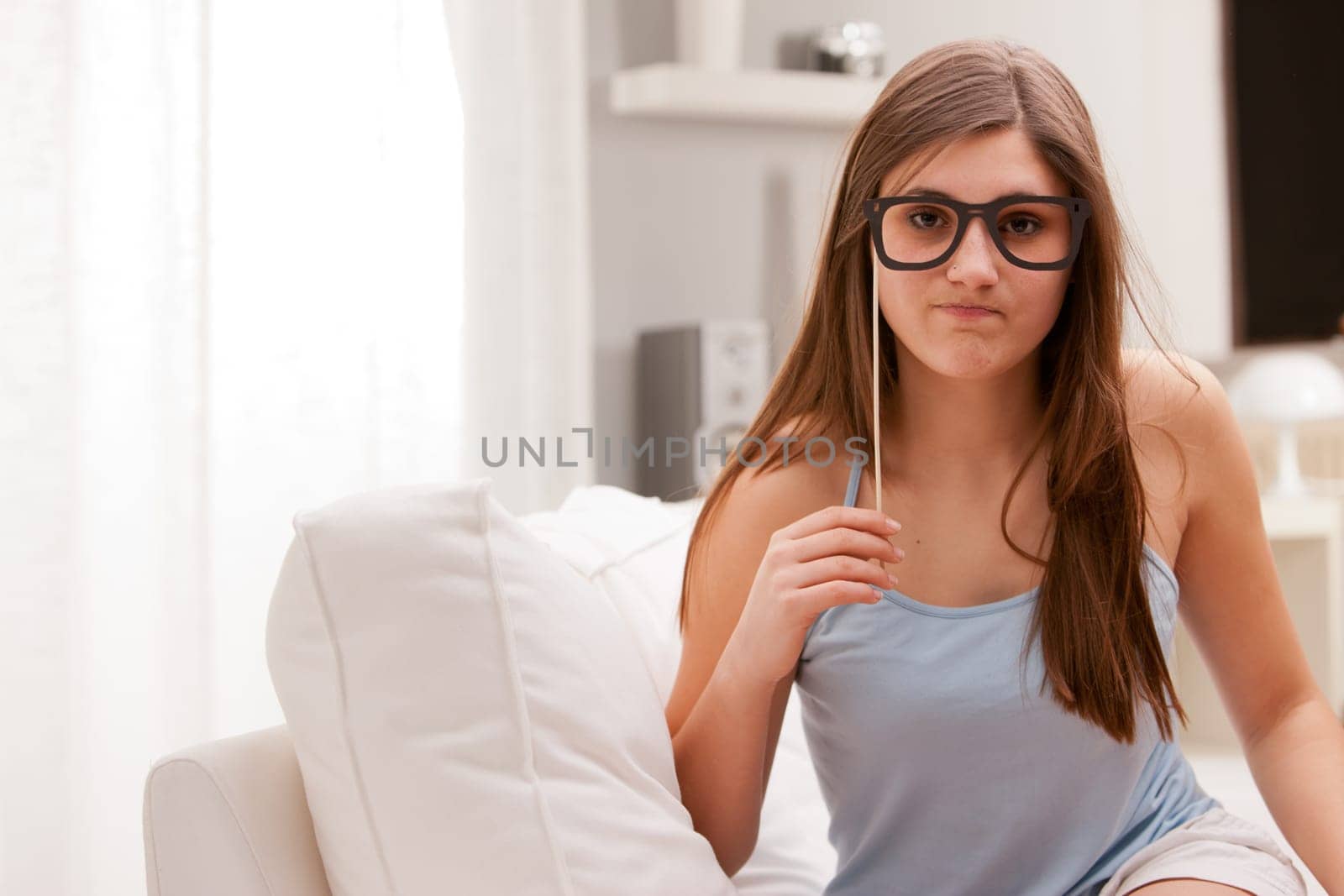 this girl is joking about being nerd or brainiac with a pair of fake carton glasses