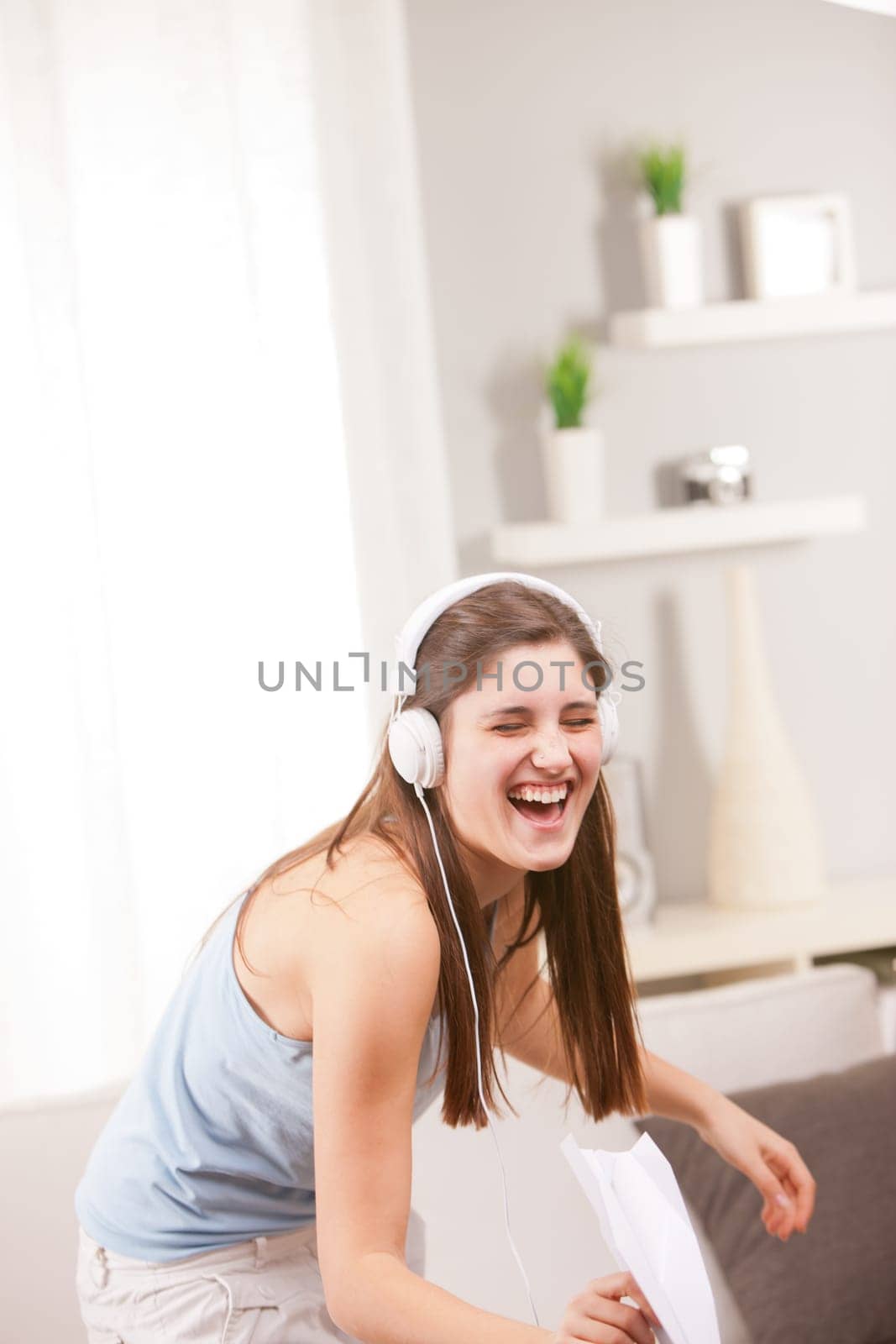 girl with an irrepressible laugh listening to music and singing out loud because she's happy