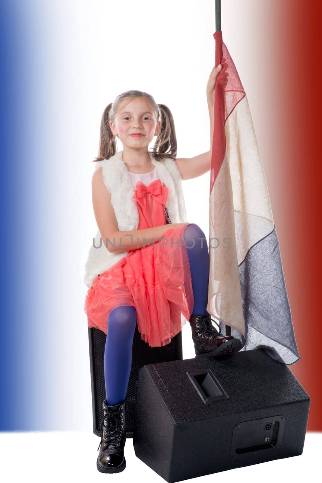 a pretty little girl sitting on a loudspeaker with a french flag